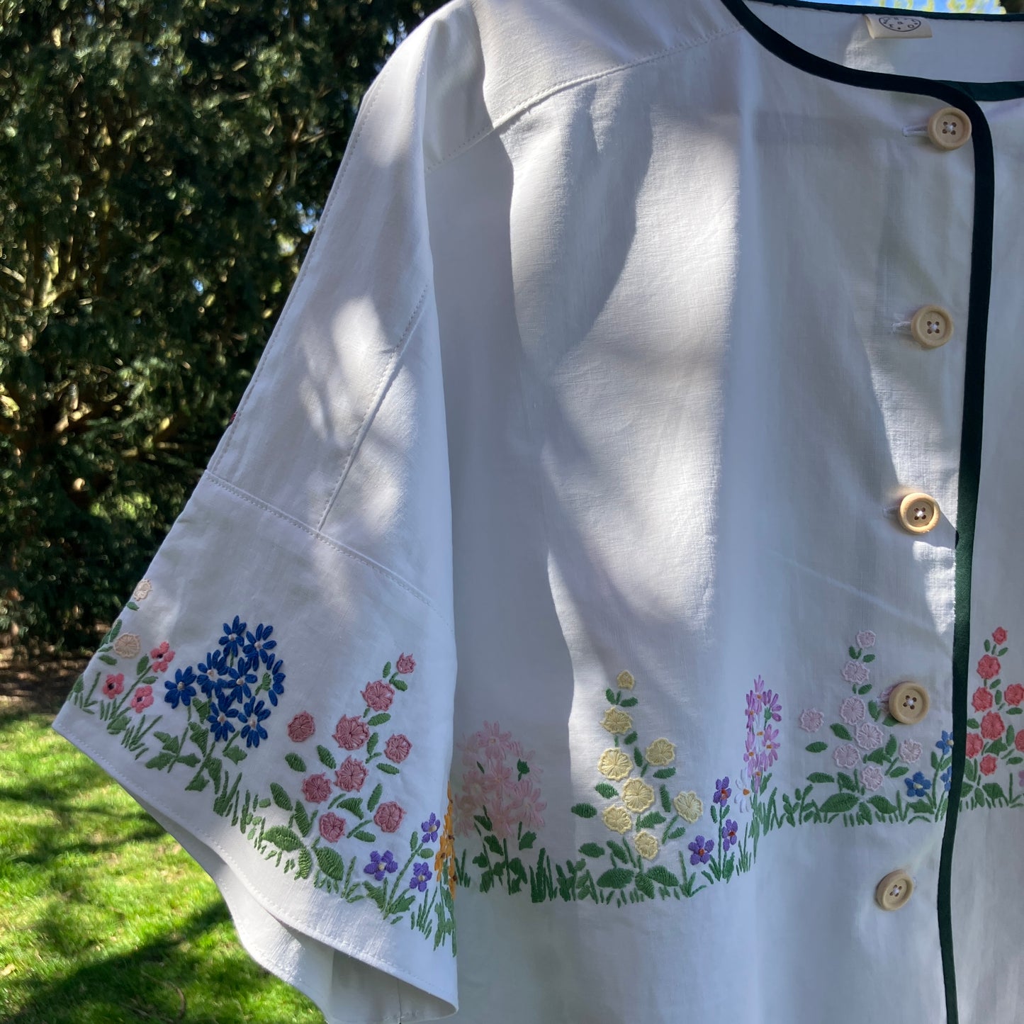 boxy top with embroidered flowers across the front and round the sleeves - and a country cottage on the back