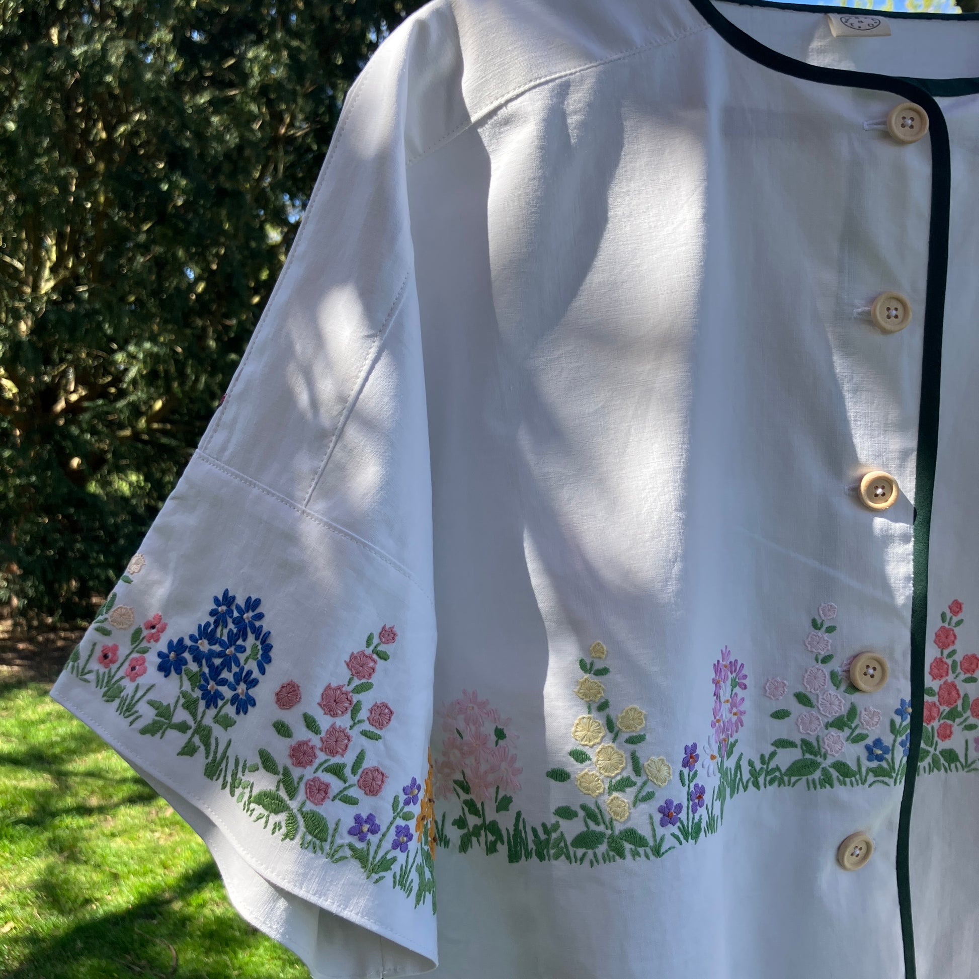 boxy top with embroidered flowers across the front and round the sleeves - and a country cottage on the back