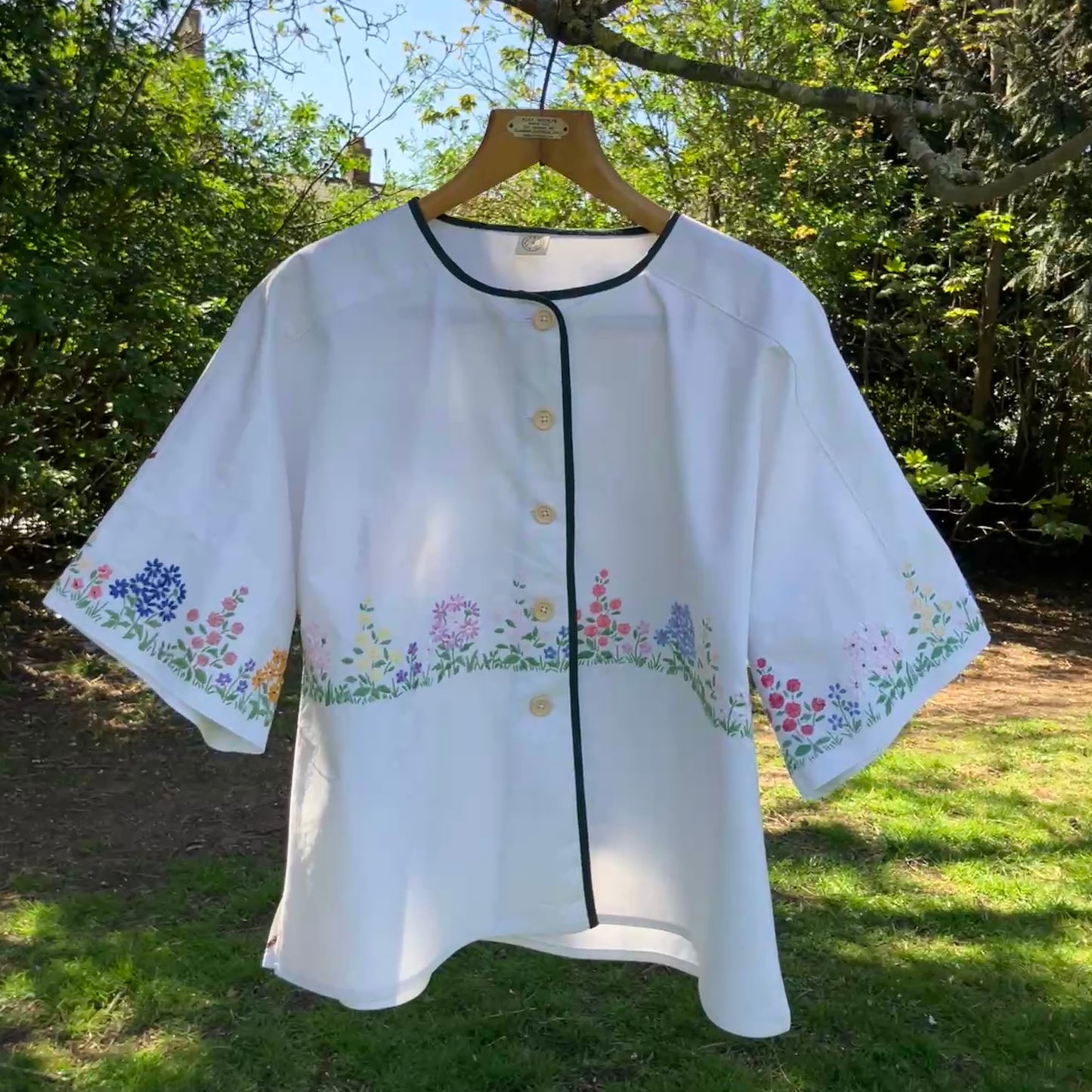 boxy top with embroidered flowers across the front and round the sleeves - and a country cottage on the back