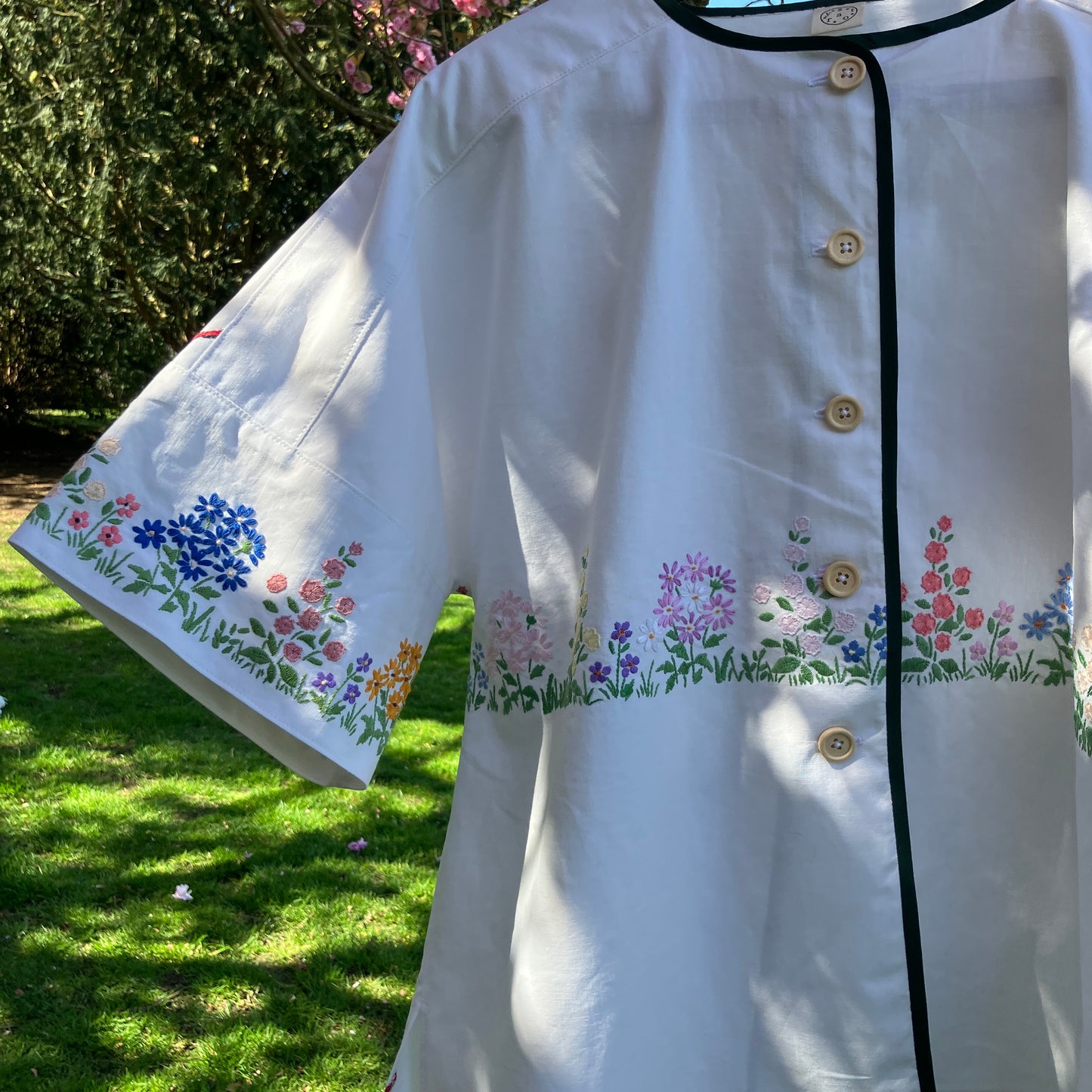 boxy top with embroidered flowers across the front and round the sleeves - and a country cottage on the back