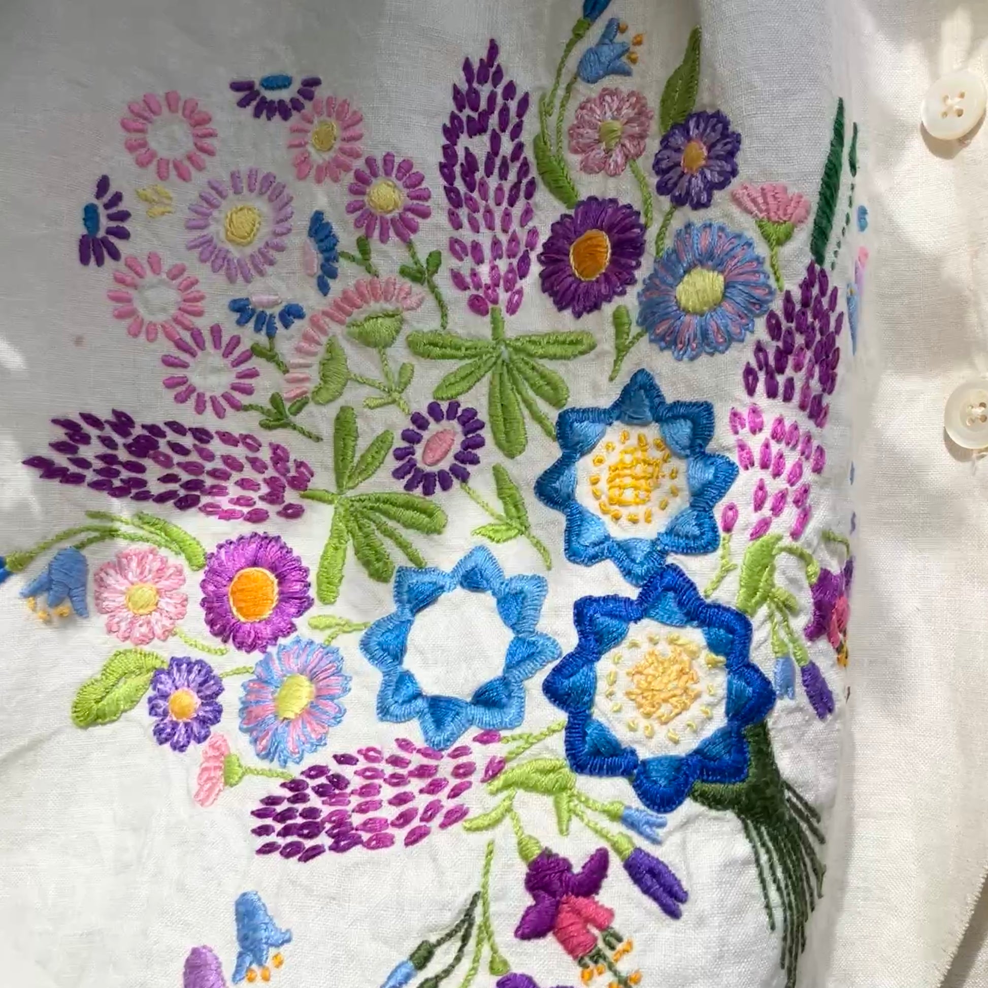 Shirt made from a recycled off-white linen tablecloth with embroidered floral design in various stages of completion