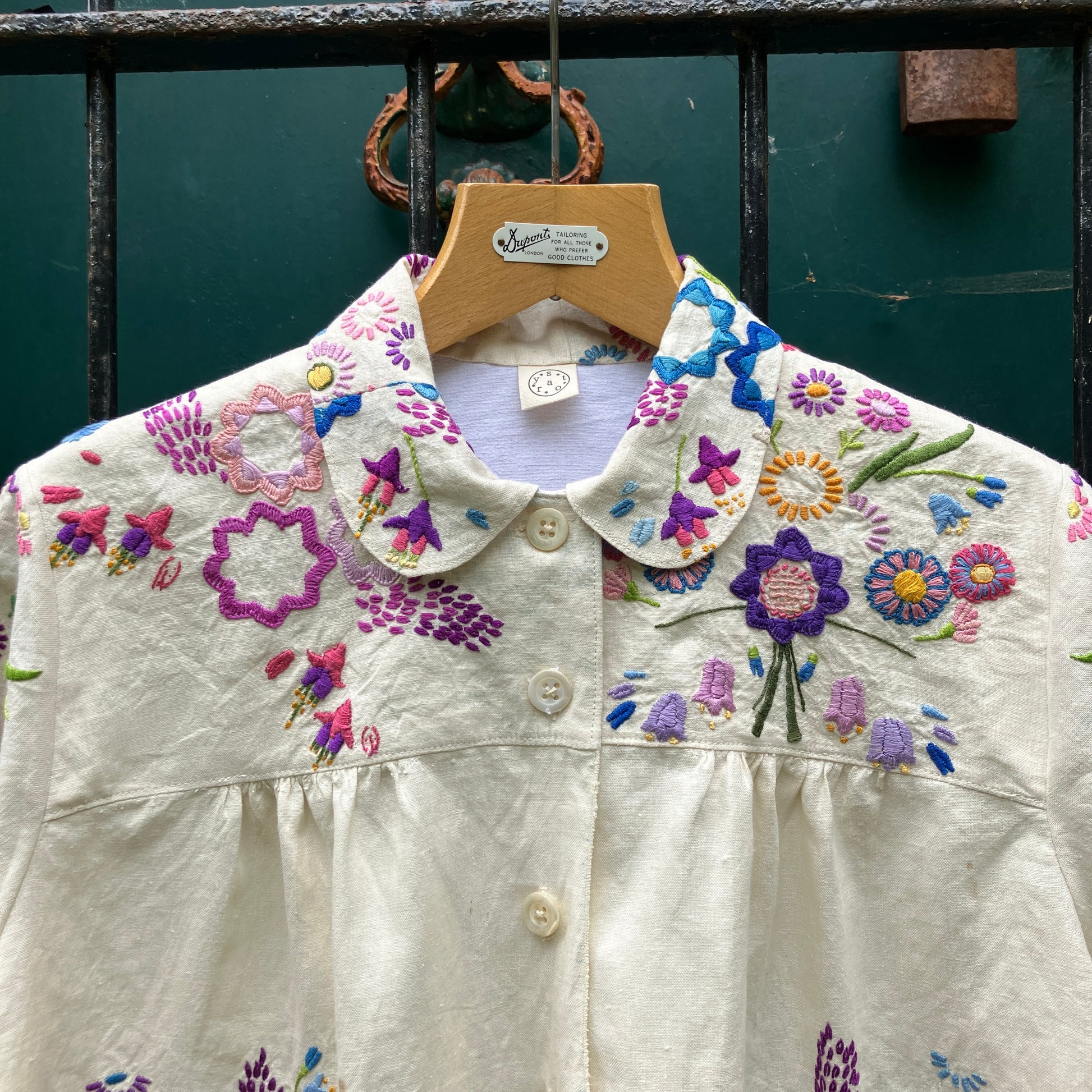 Shirt made from a recycled off-white linen tablecloth with embroidered floral design in various stages of completion