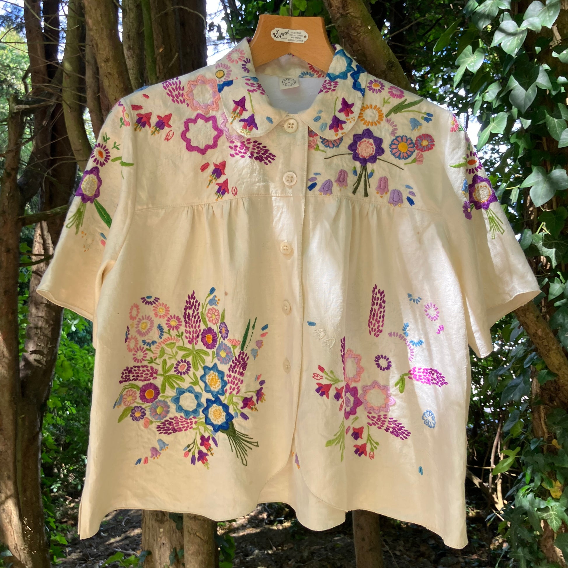 Shirt made from a recycled off-white linen tablecloth with embroidered floral design in various stages of completion