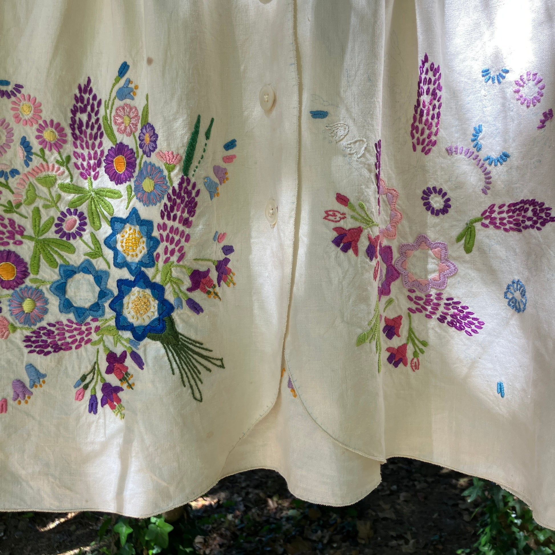Shirt made from a recycled off-white linen tablecloth with embroidered floral design in various stages of completion