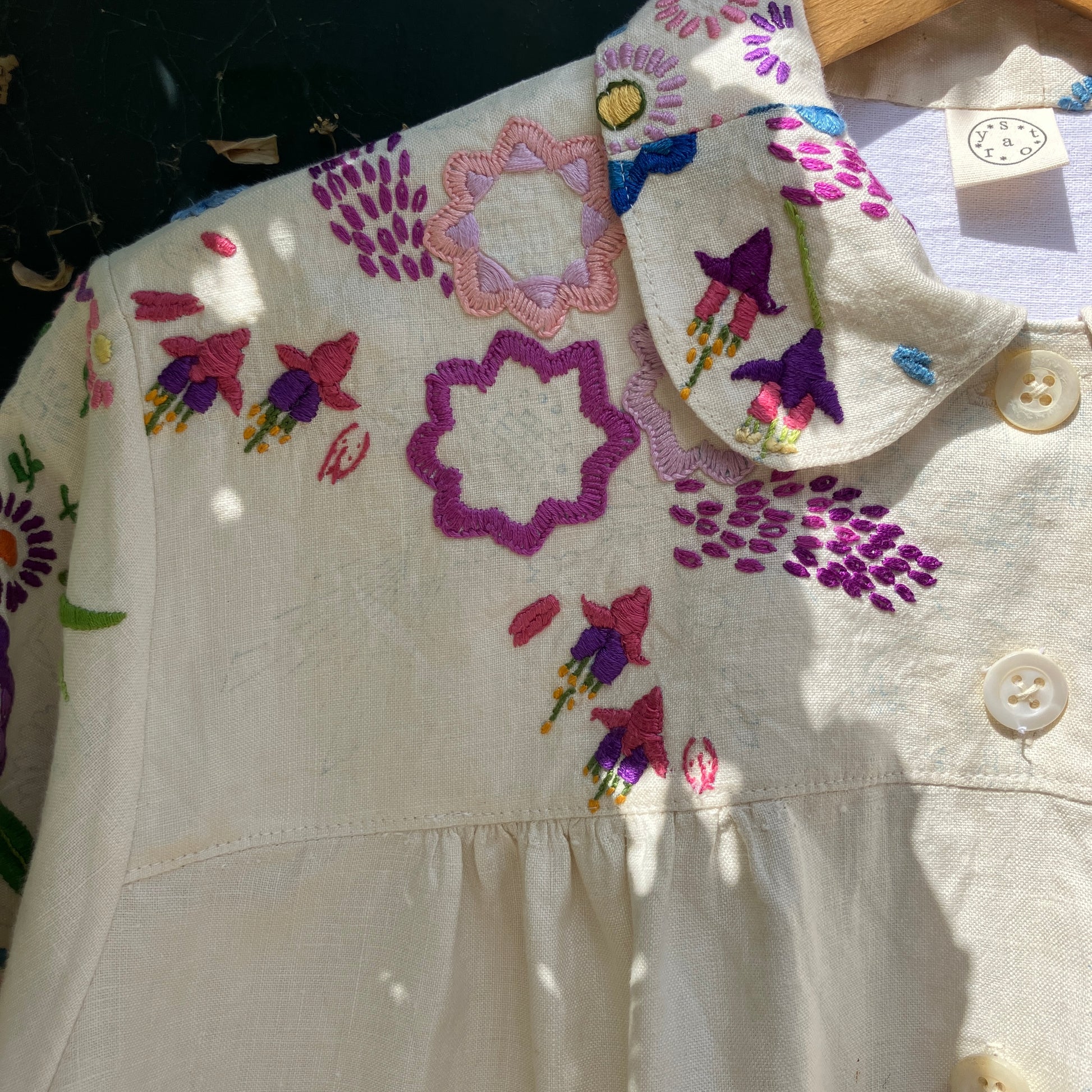 Shirt made from a recycled off-white linen tablecloth with embroidered floral design in various stages of completion
