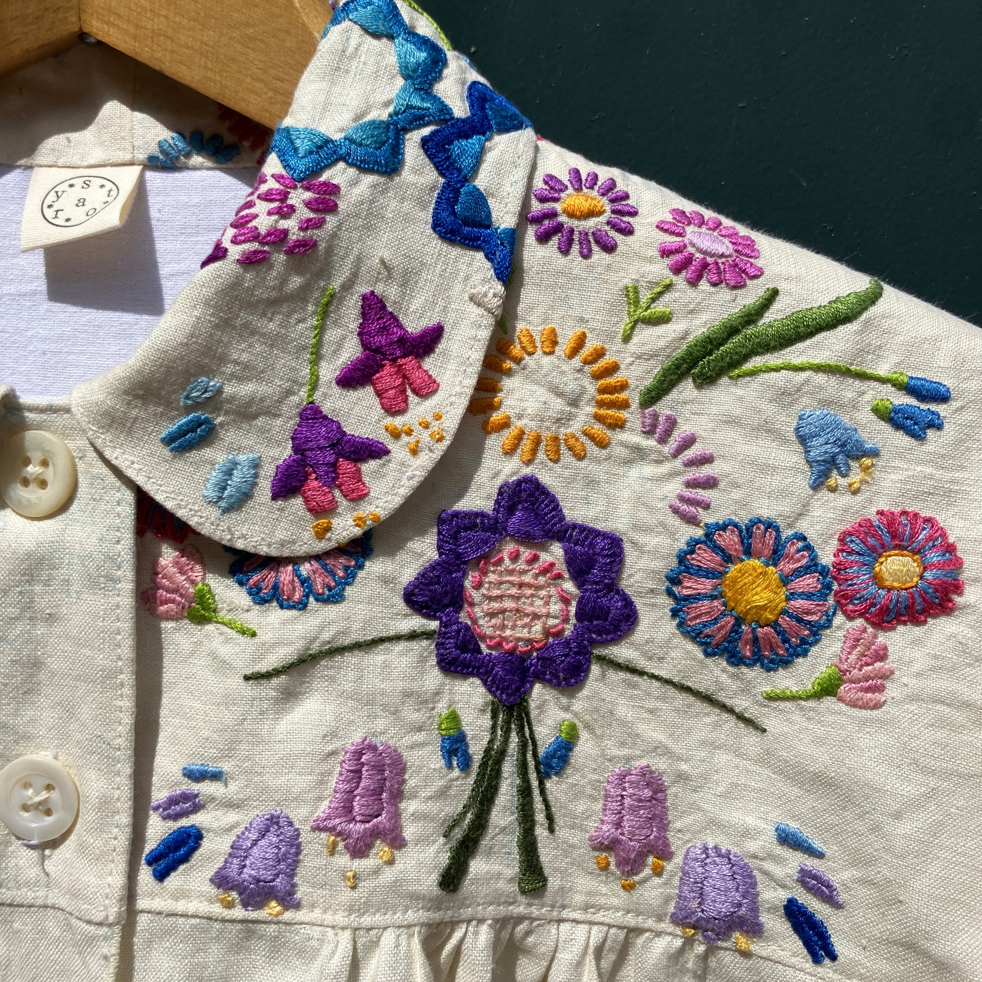 Shirt made from a recycled off-white linen tablecloth with embroidered floral design in various stages of completion