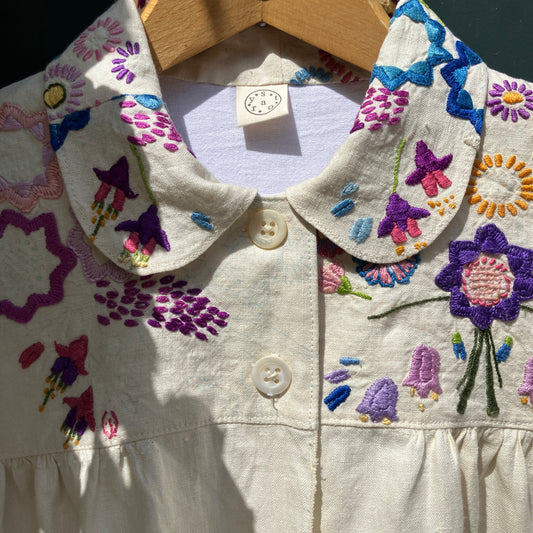 Shirt made from a recycled off-white linen tablecloth with embroidered floral design in various stages of completion