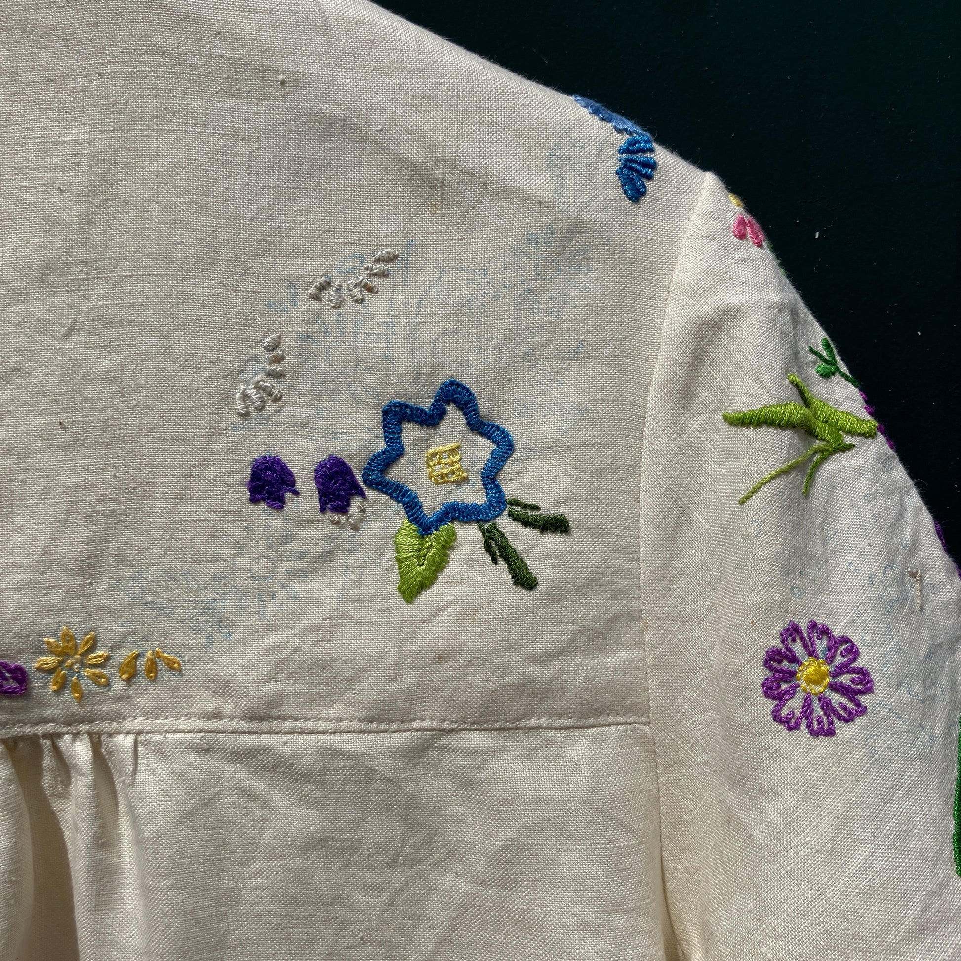 Shirt made from a recycled off-white linen tablecloth with embroidered floral design in various stages of completion