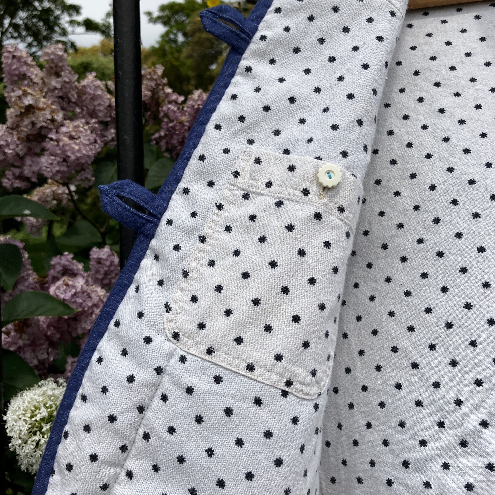 Vest/gilet/waistcoat made from a reclaimed blue checkerboard weave Irish wool Gaiety blanket, photographed in front of a lilac bush (close-up of inside pocket)