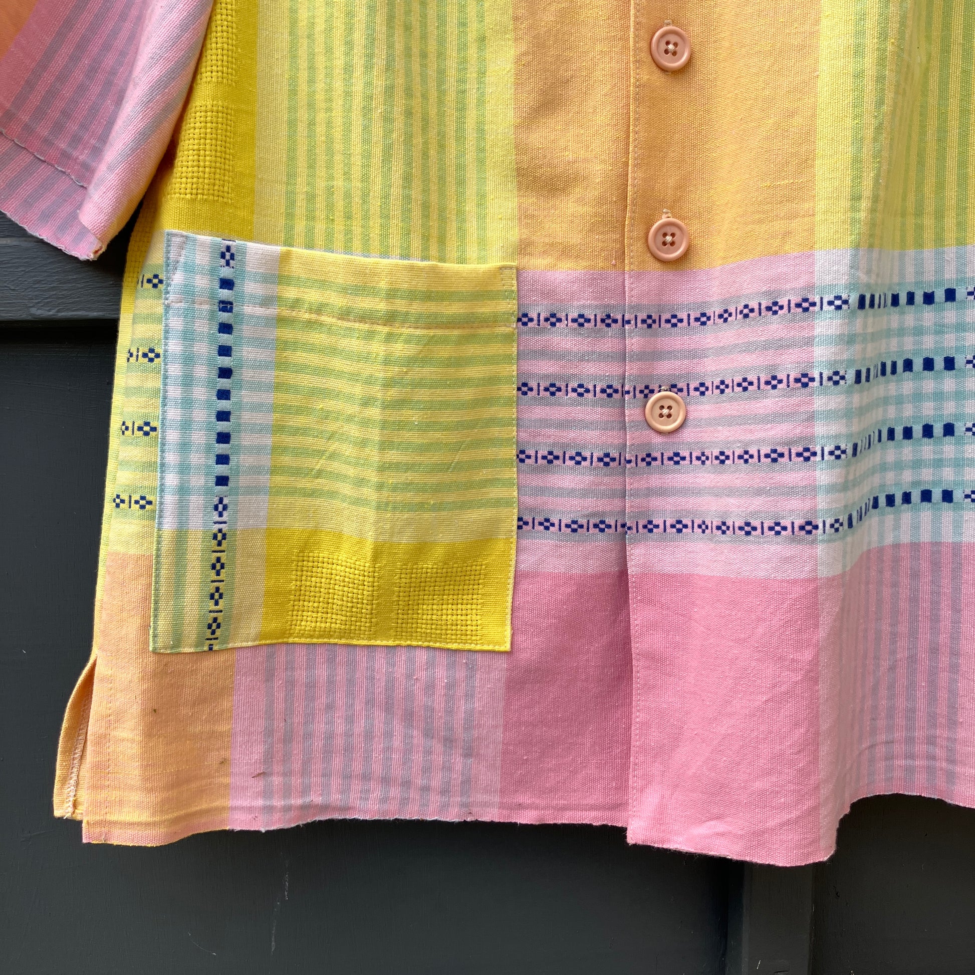 Shirt made from a reclaimed cotton tablecloth in shades of pink, blue, peach and bright yellow (detail of pocket)