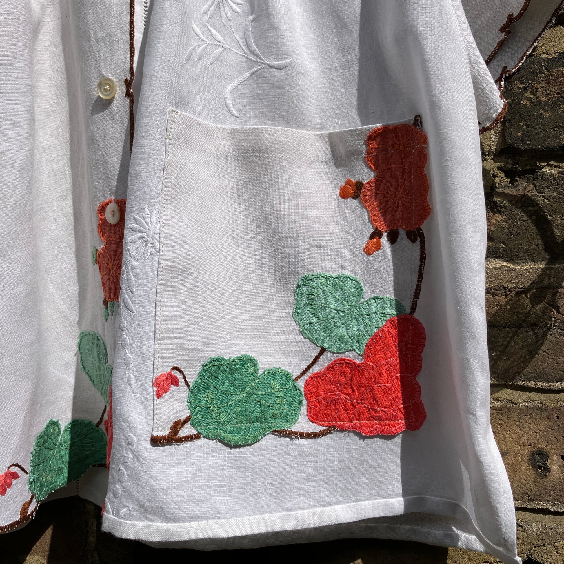 summer top hand made from a reclaimed tablecloth with appliqué nasturtiums in red, orange, peach and green (close-up of pocket)