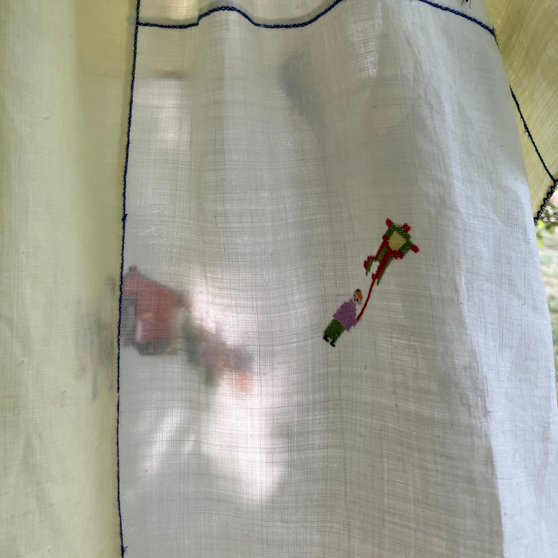 Shirt made from a found vintage tablecloth with a parade of small embroidered figures holding signs, kites and lanterns