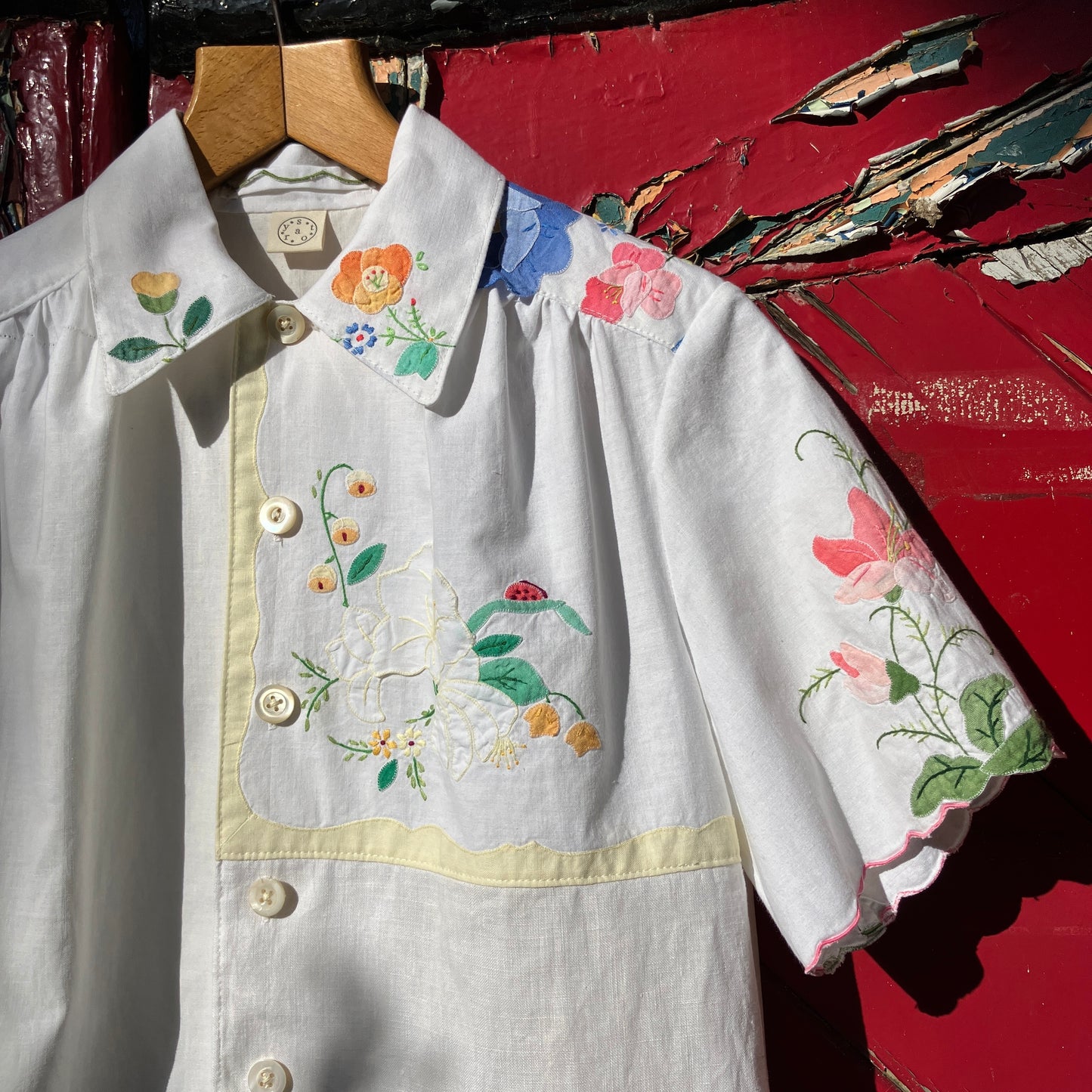 linen and cotton shirt made from a patchwork of reclaimed vintage napkins and placemats with detailed appliqué flowers and pastel borders
