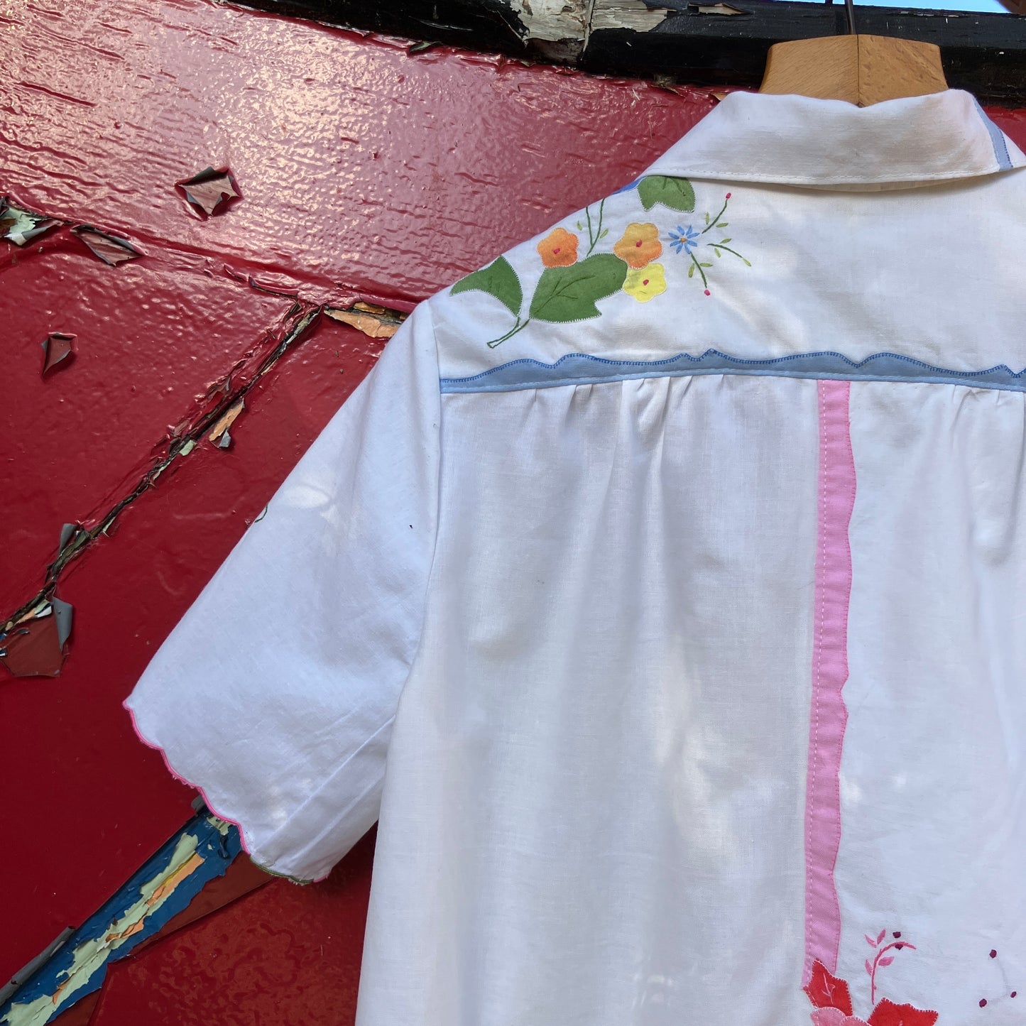 linen and cotton shirt made from a patchwork of reclaimed vintage napkins and placemats with detailed appliqué flowers and pastel borders