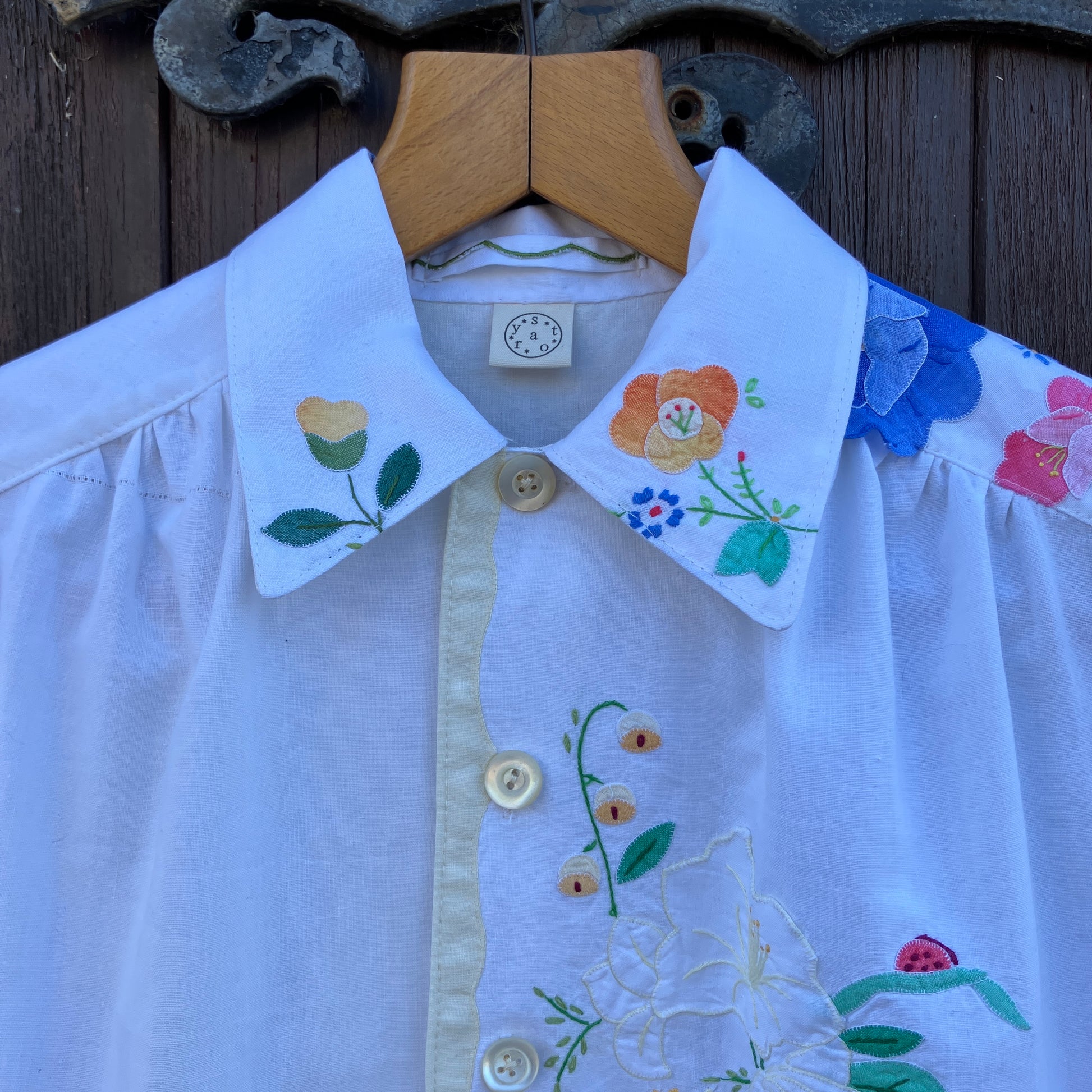 linen and cotton shirt made from a patchwork of reclaimed vintage napkins and placemats with detailed appliqué flowers and pastel borders