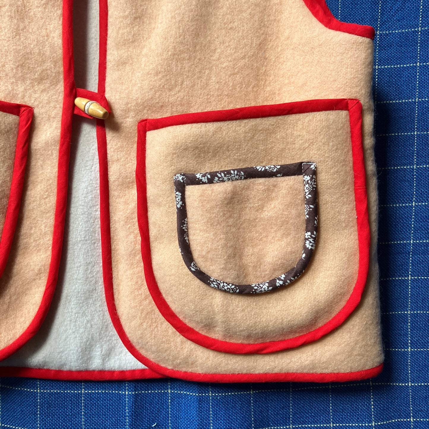 Vest/waistcoat made from a recycled vintage pink wool blanket, with red cotton binding and vintage wooden toggles
