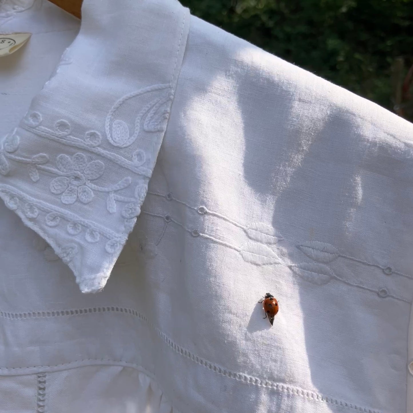 Blouse made from recycled table linen on a hanger against a natural background