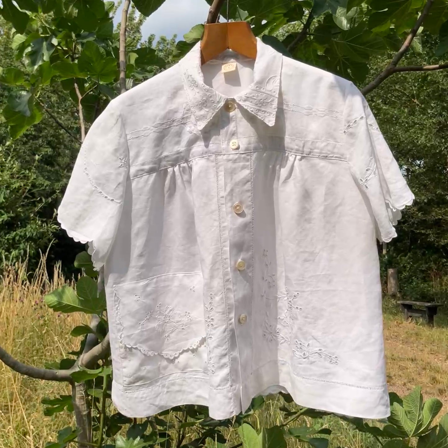 Blouse made from recycled table linen on a hanger against a natural background