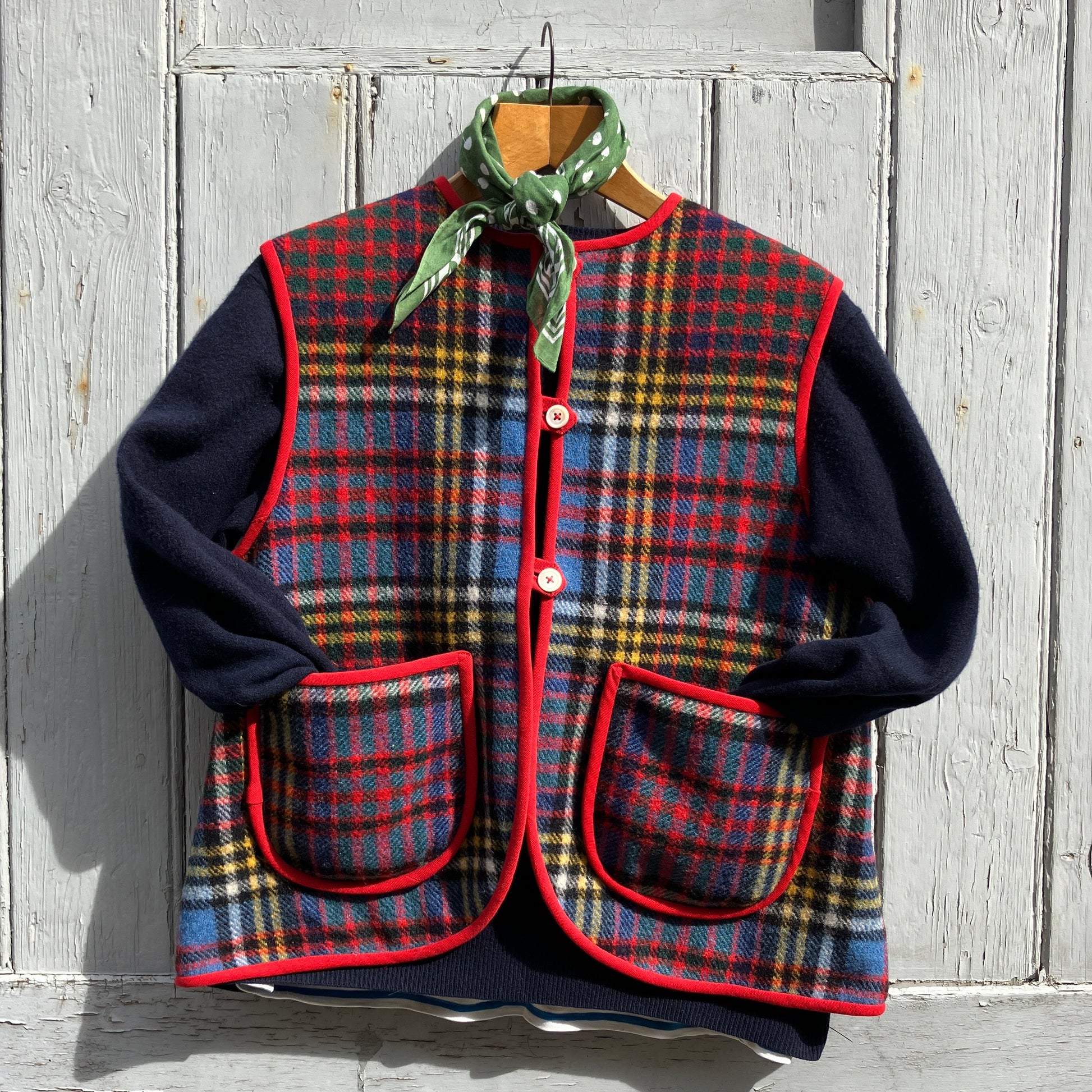 Vest/waistcoat/gilet handmade from a recycled tartan wool blanket. With red binding, two patch pockets and three shell buttons. Pictured as an outfit, with a navy jumper underneath and a green neckerchief