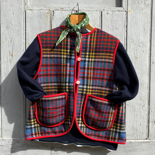 Vest/waistcoat/gilet handmade from a recycled tartan wool blanket. With red binding, two patch pockets and three shell buttons. Pictured as an outfit, with a navy jumper underneath and a green neckerchief