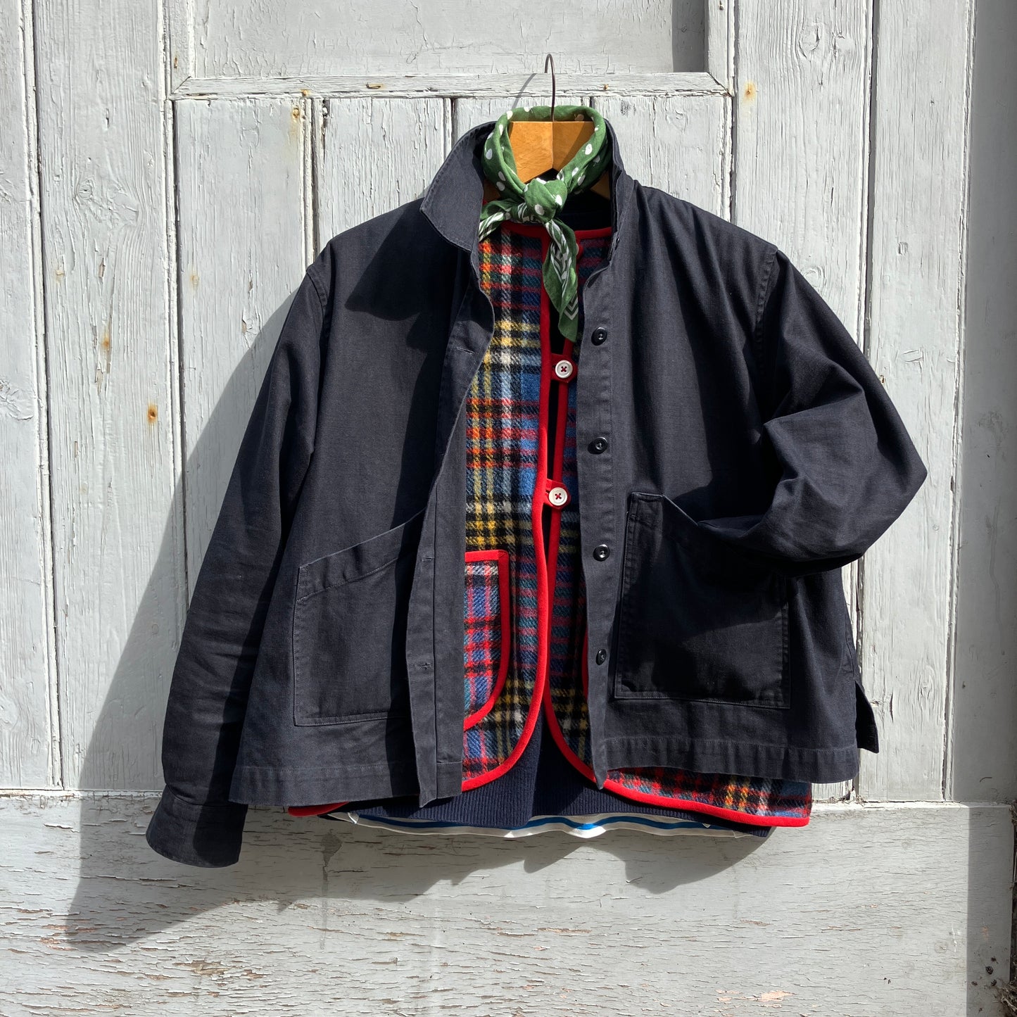 Vest/waistcoat/gilet handmade from a recycled tartan wool blanket. With red binding, two patch pockets and three shell buttons. Pictured as an outfit, with a navy jumper underneath, a navy jacket on top and a green neckerchief