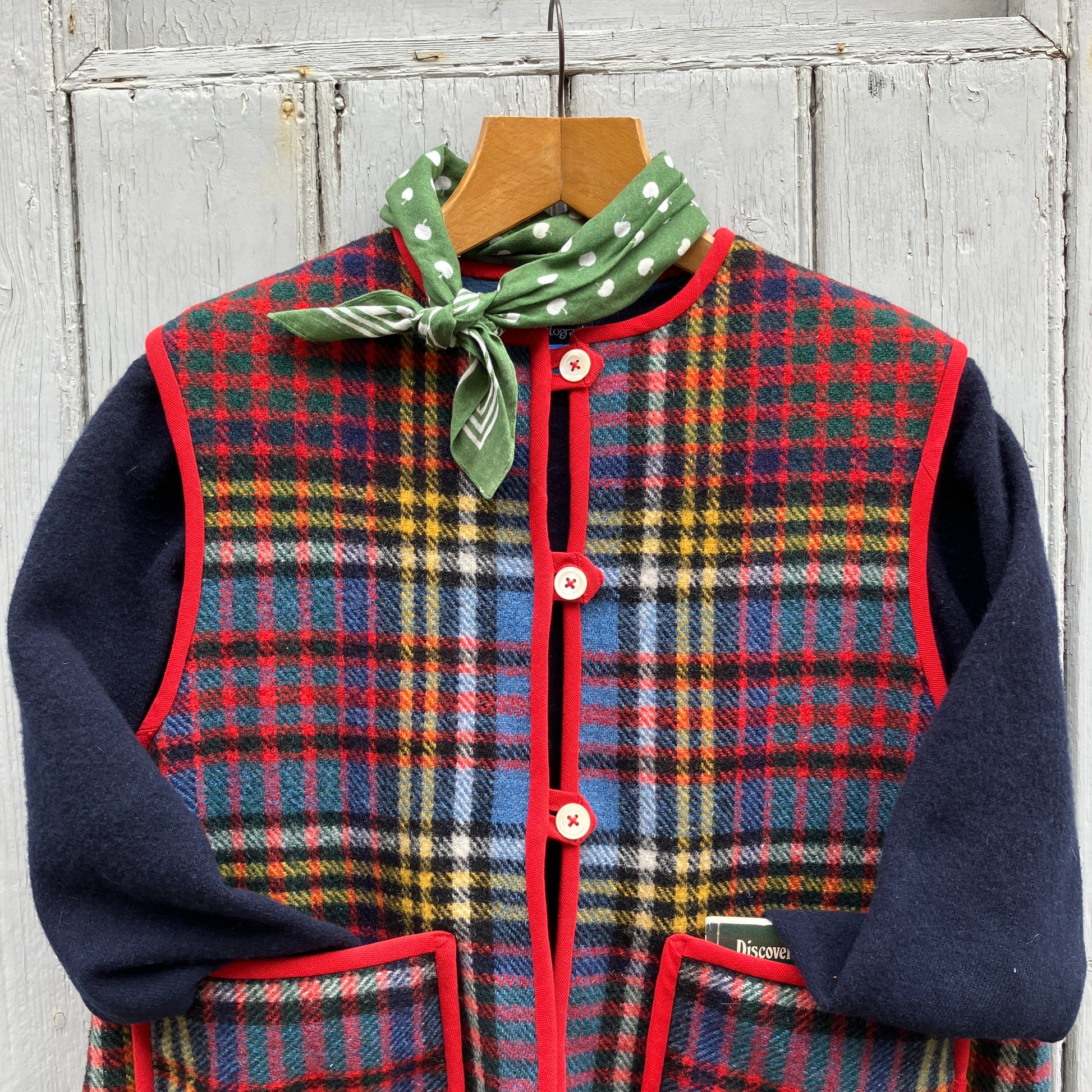 Vest/waistcoat/gilet handmade from a recycled tartan wool blanket. With red binding, two patch pockets and three shell buttons. Pictured as an outfit, with a navy jumper underneath and a green neckerchief