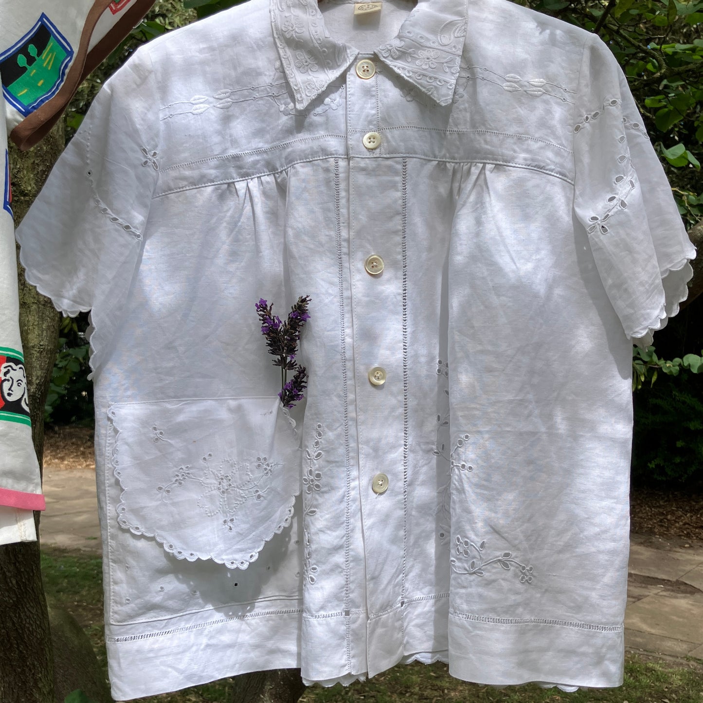Blouse made from recycled table linen on a hanger against a natural background
