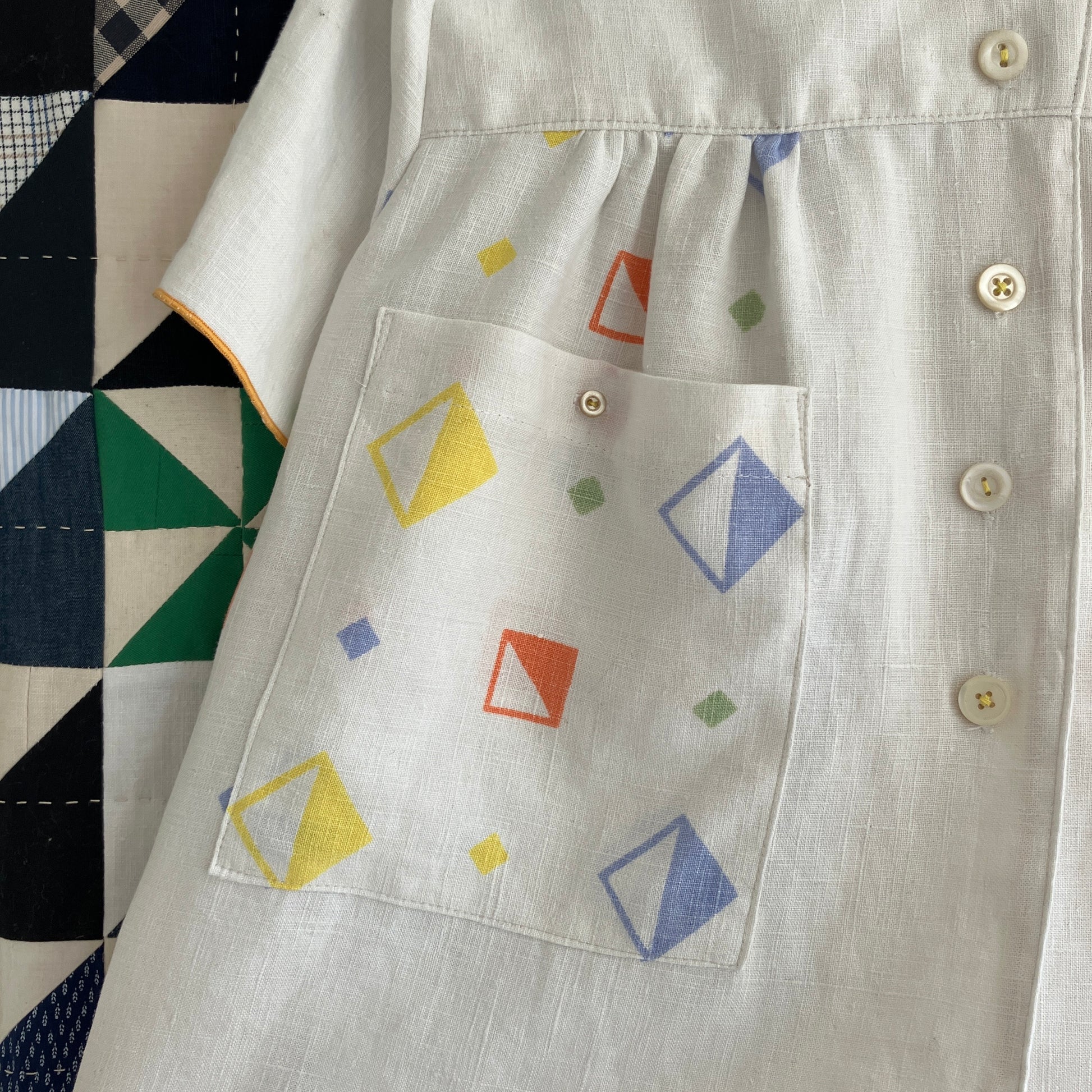 One-of-a-kind shirt handmade from a beautifully soft reclaimed off-white linen tablecloth with a cool geometric print. Photographed against a patchwork quilt (detail of pocket)