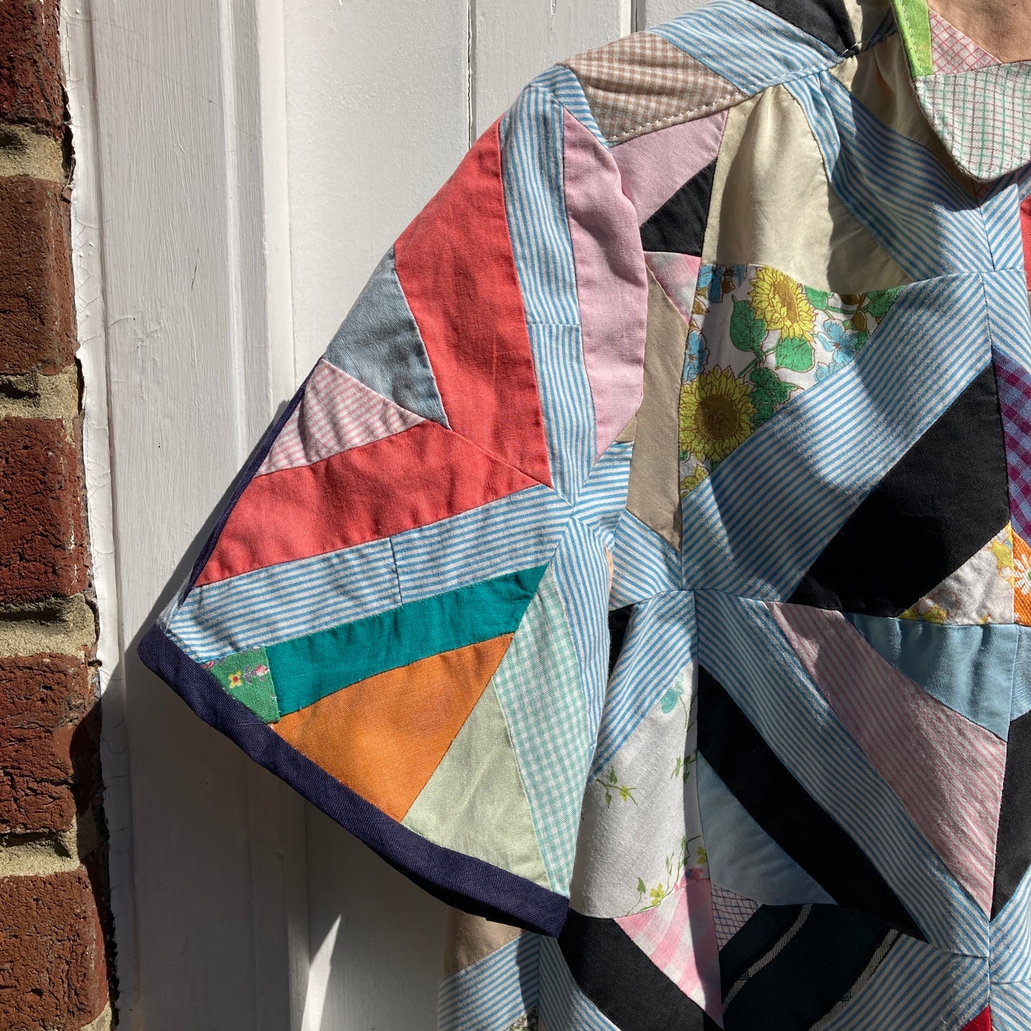 Short-sleeved shirt made from a found piece of 60s/70s patchwork in various bright and pastel colours (close-up of sleeve)