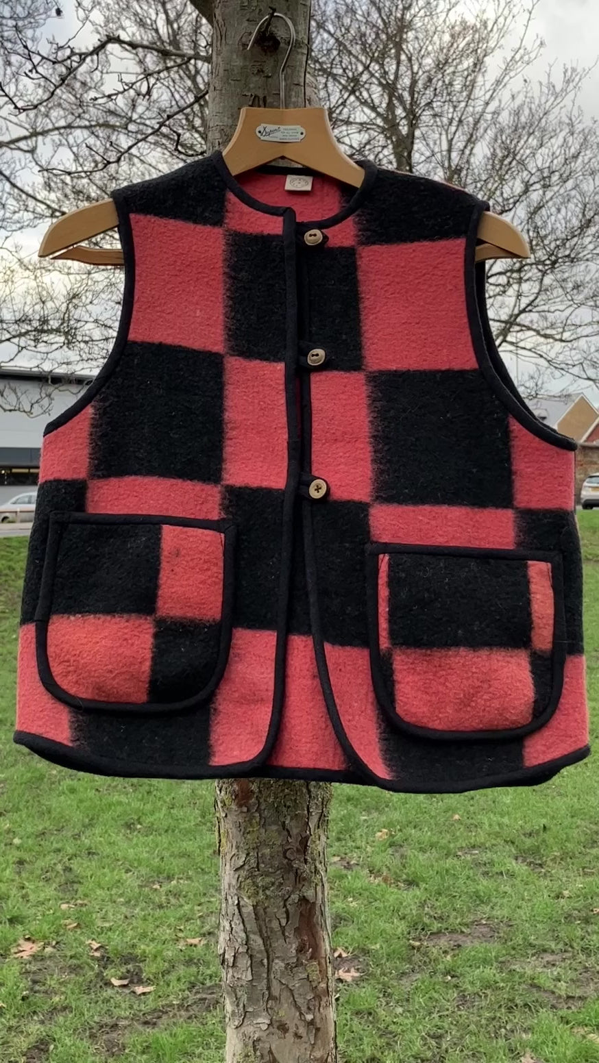 Short video of a cosy gilet/waistcoat/bodywarmer made from a fabulous pink and black checkerboard reclaimed wool blanket hanging in a tree and moving in the breeze