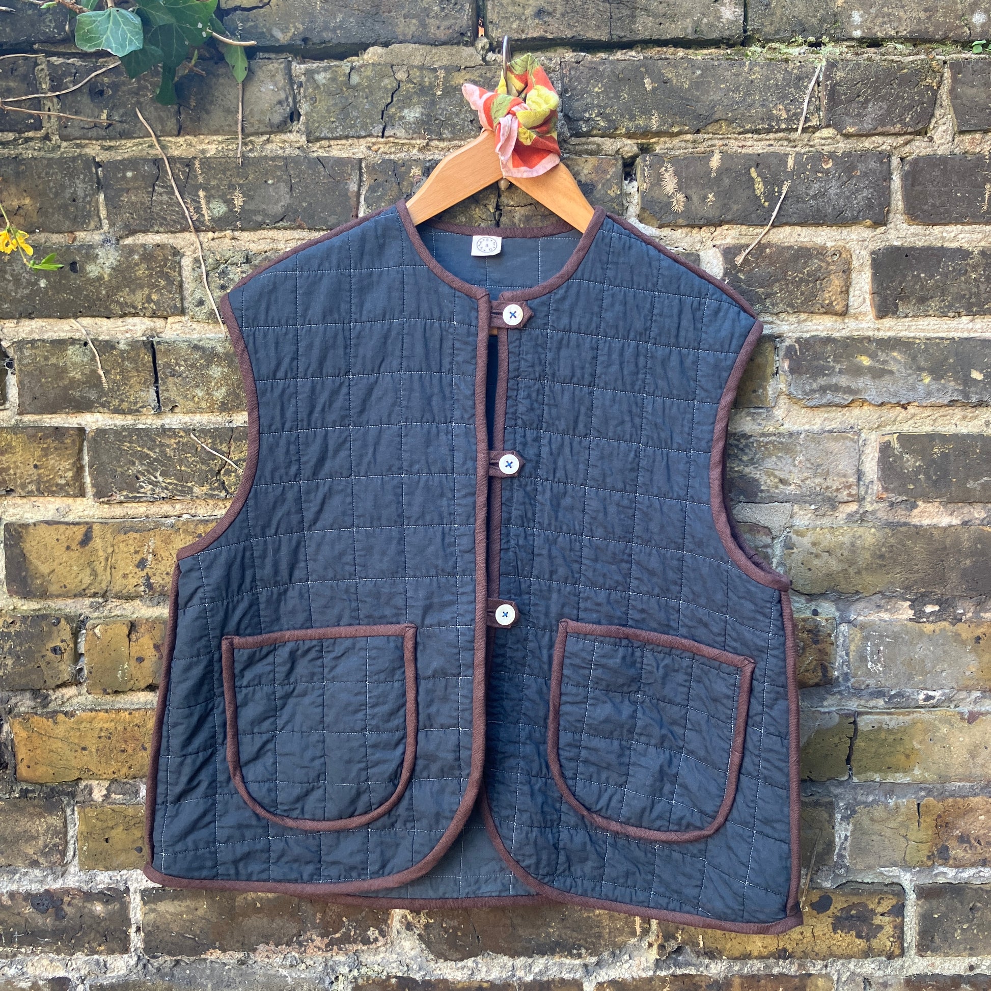 Super useful vest/gilet/bodywarmer/waistcoat handmade from a reclaimed black cotton quilt. Features two large patch pockets, three found shell buttons and brown linen binding.
