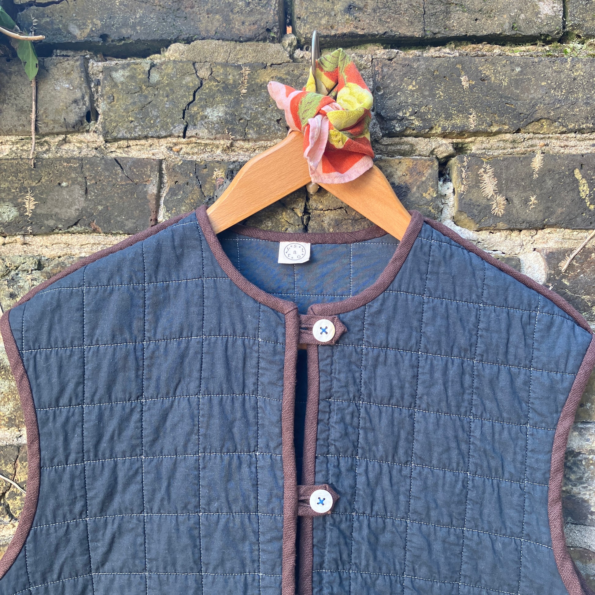 Super useful vest/gilet/bodywarmer/waistcoat handmade from a reclaimed black cotton quilt. Features two large patch pockets, three found shell buttons and brown linen binding.