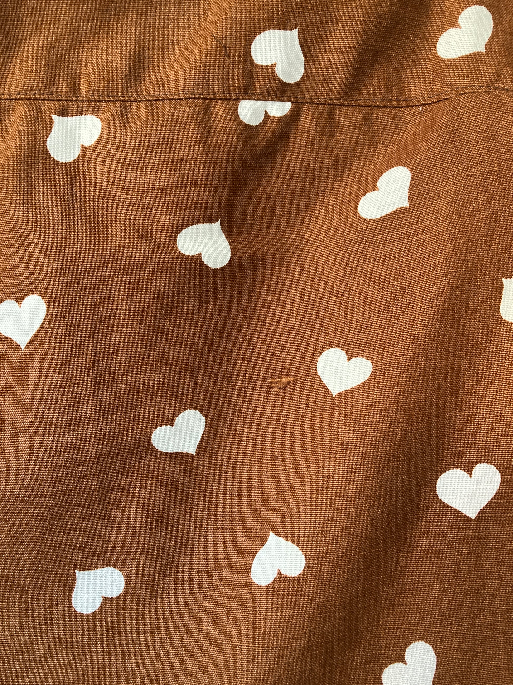 close-up of brown heart-print tie front top made from a recycled tablecloth, showing a minor flaw in the weave of the fabric