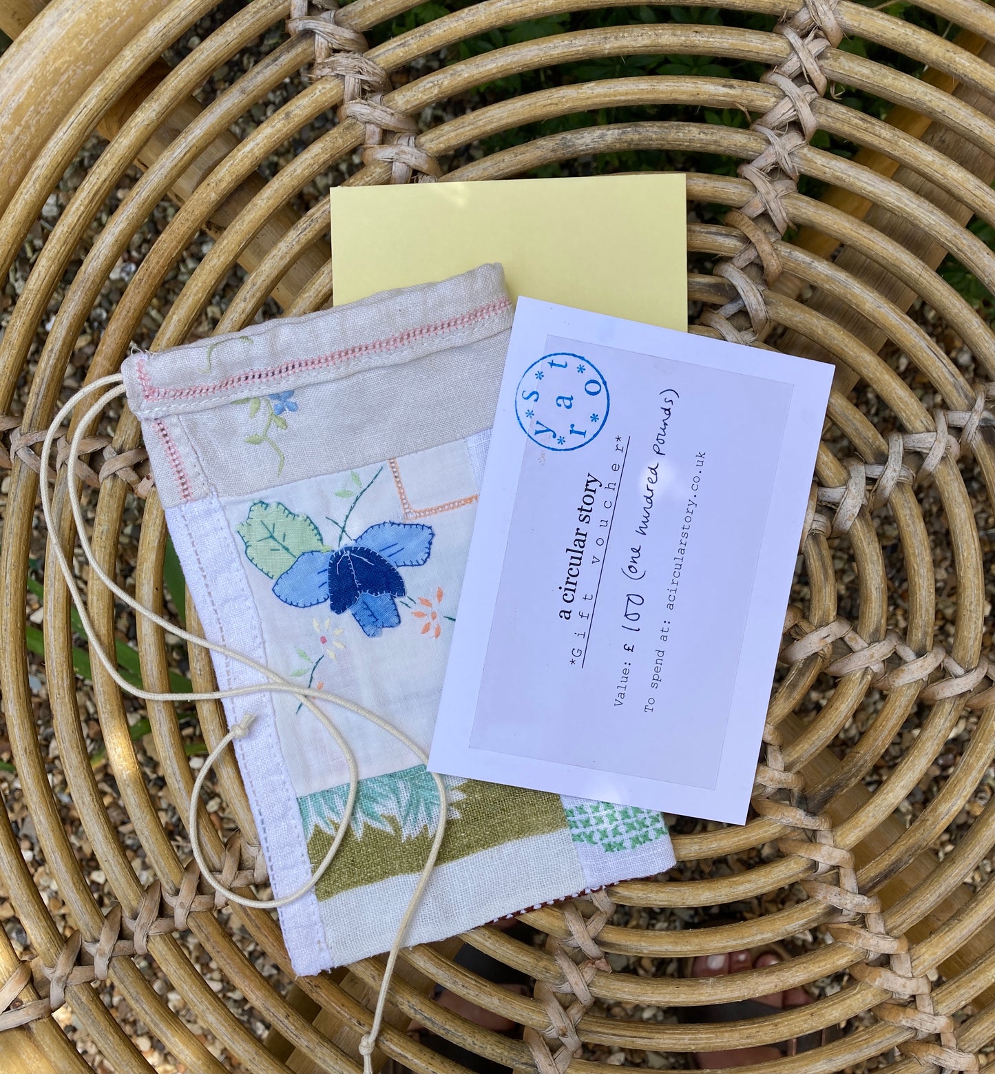 A Circular Story gift voucher alongside a patchwork scrap bag, photographed on a wicker table