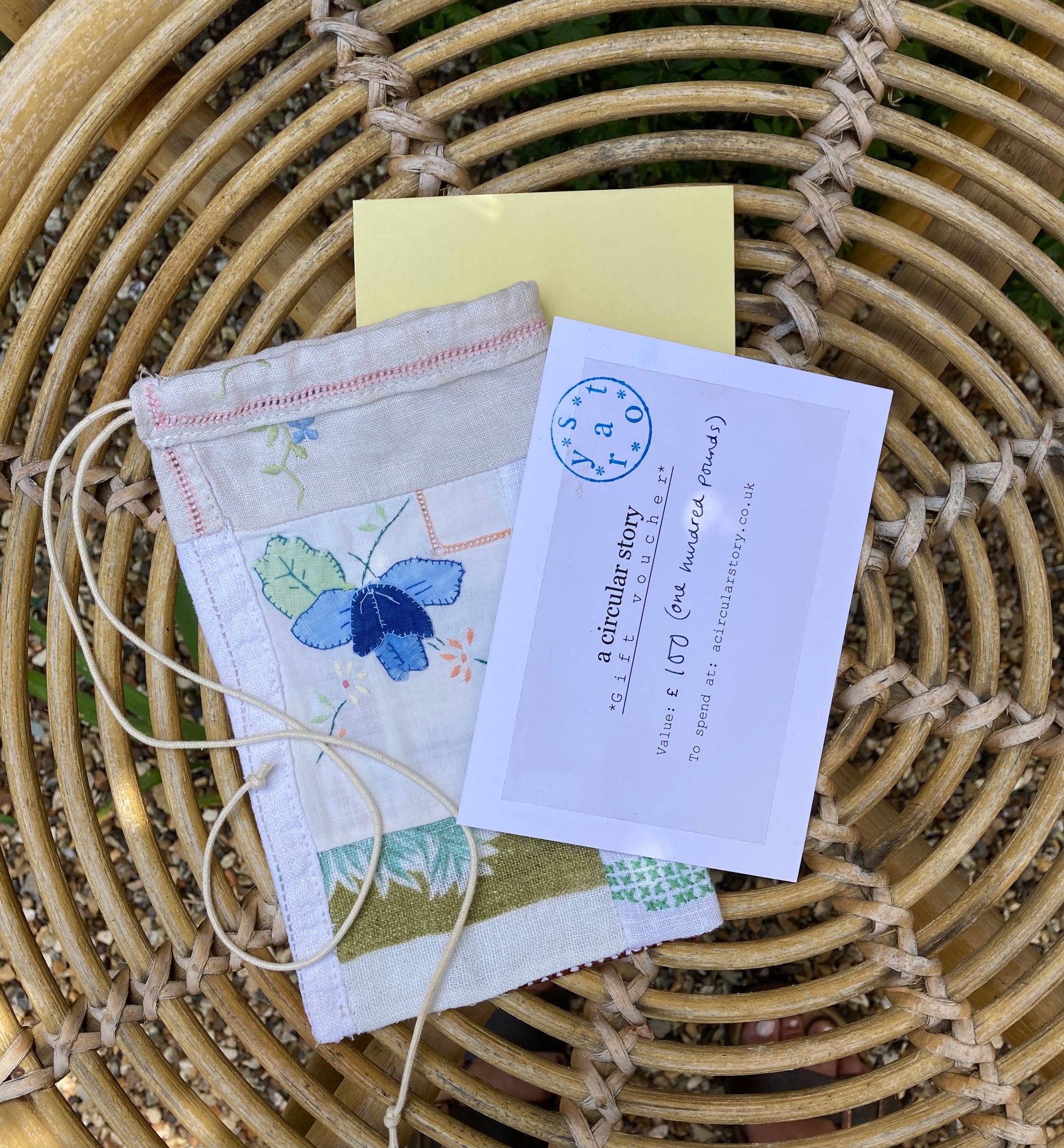 A Circular Story gift voucher alongside a patchwork scrap bag, photographed on a wicker table