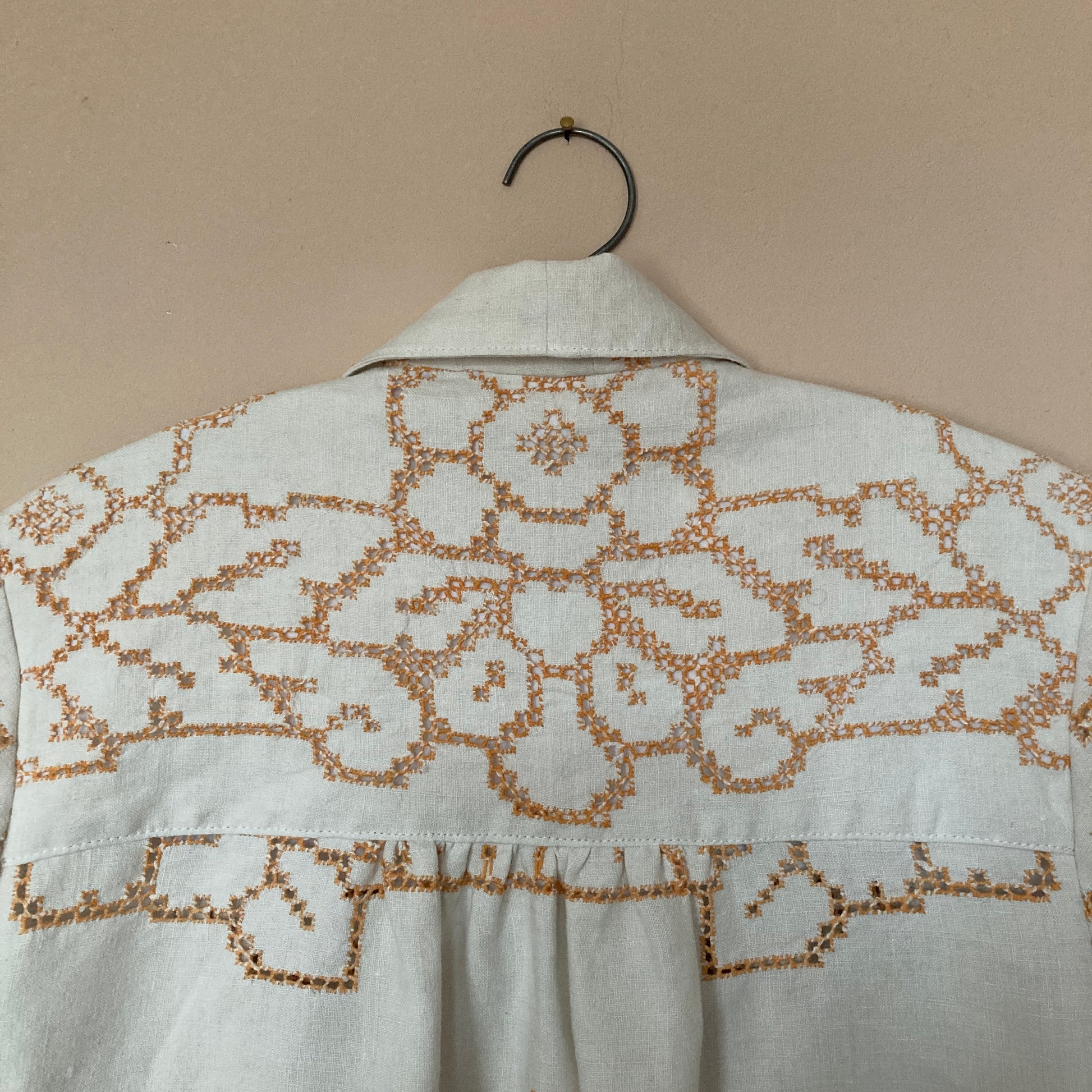 Short-sleeved shirt made from a recycled off-white linen tablecloth with orange cutwork pattern (detail of back yoke)