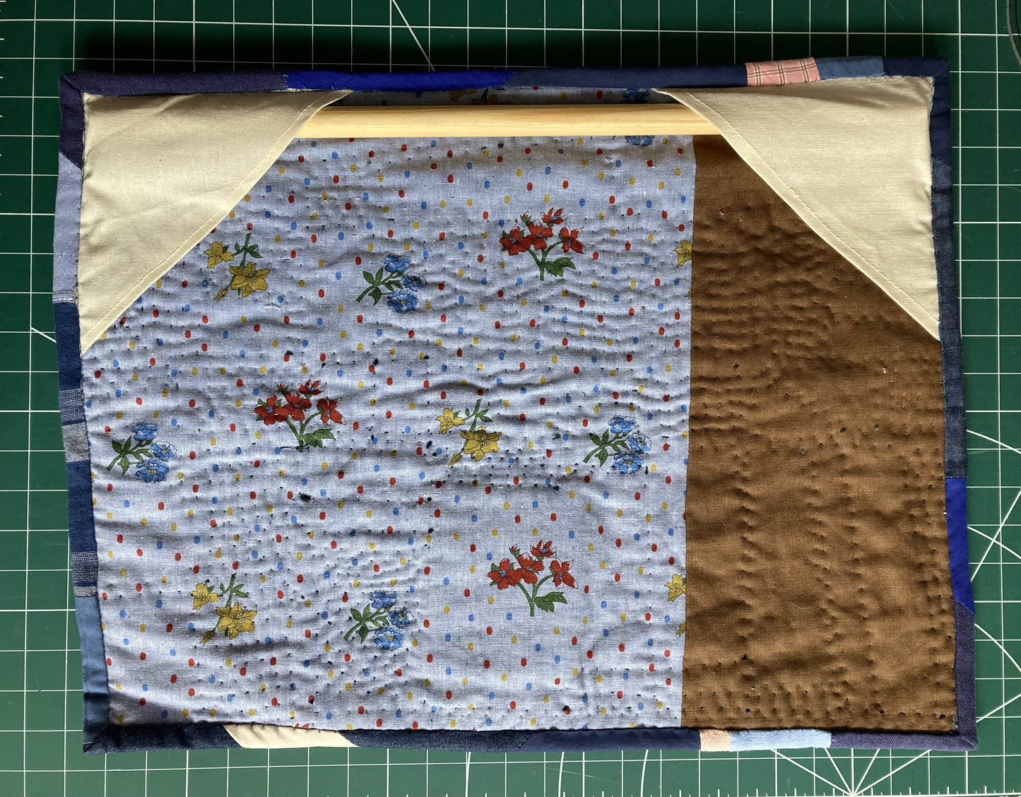 Wallhanging made from precious blue-coloured scraps patchworked together and quilted in an improv fashion, image shows the back