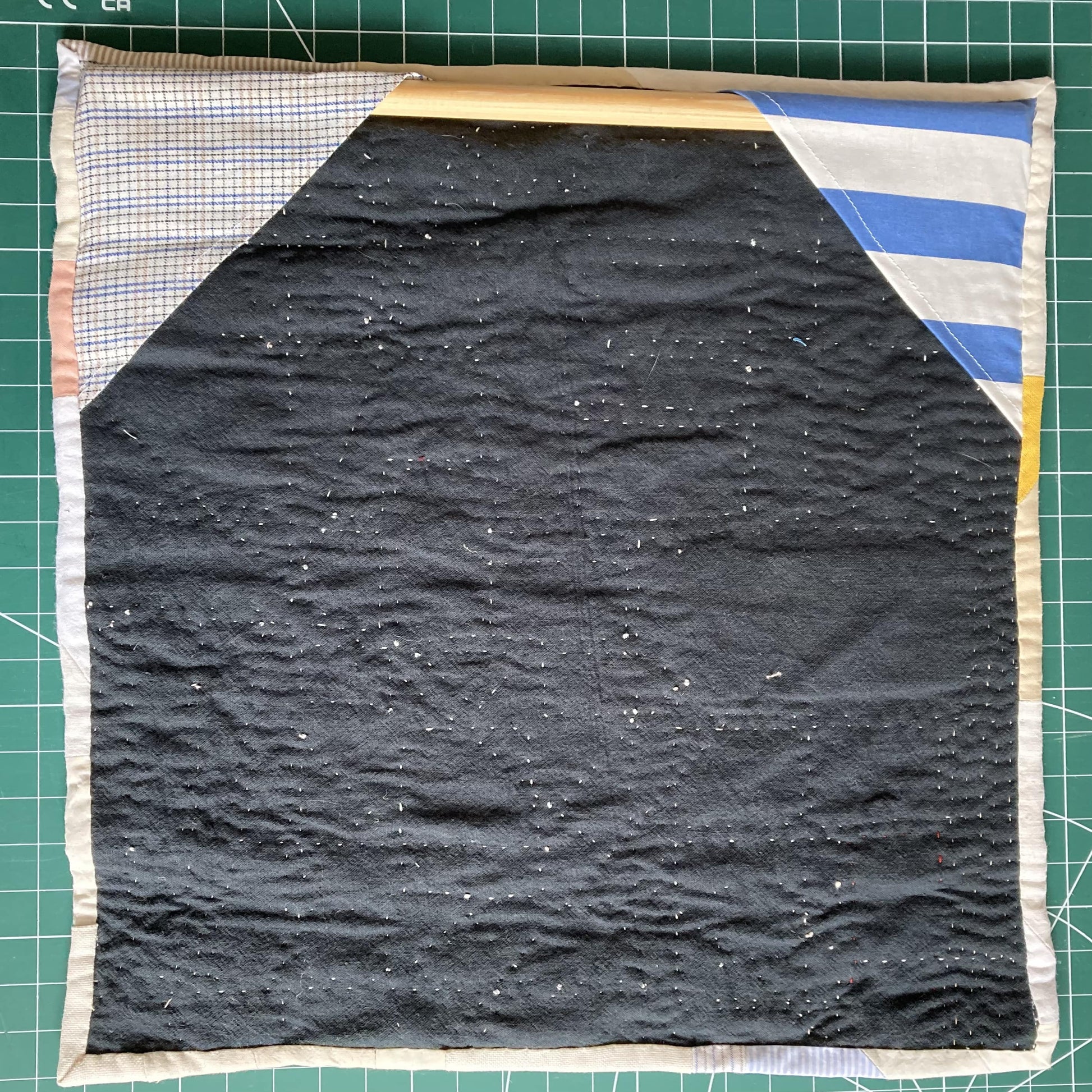 Wallhanging made from precious neutral and pastel-coloured scraps patchworked together and quilted in an improv fashion, image shows the back