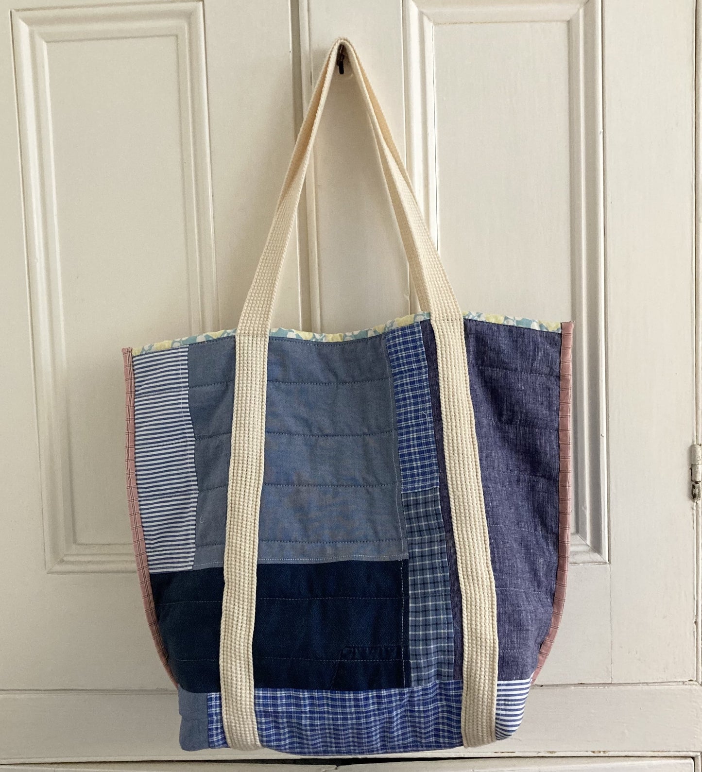 Quilted patchwork tote bag hand made from reclaimed cotton shirts. Large, deep pocket on the front. Image shows the reverse