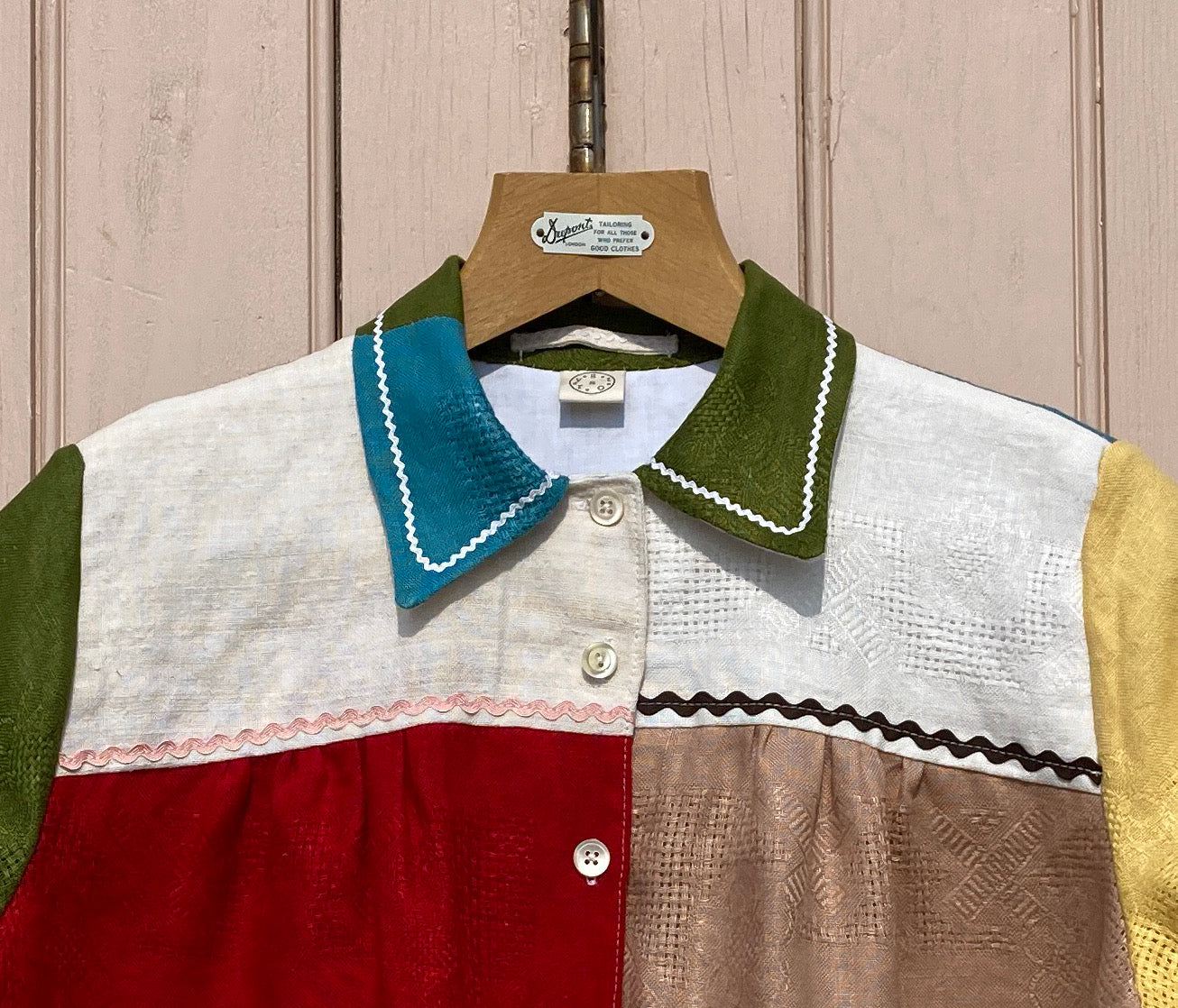 Short-sleeved shirt made from a patchwork of multicoloured vintage linen napkins (close up, showing ricrac details on yoke and collar)