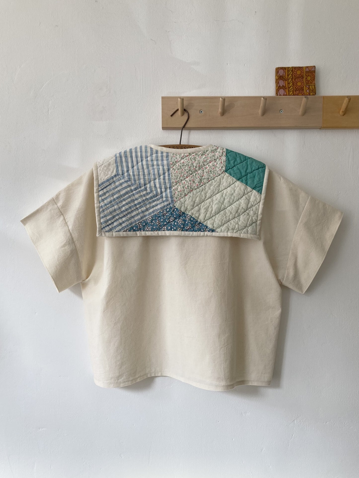 Boxy short-sleeved top made from found calico with a sailor collar cut from an antique patchwork quilt, image shows the back