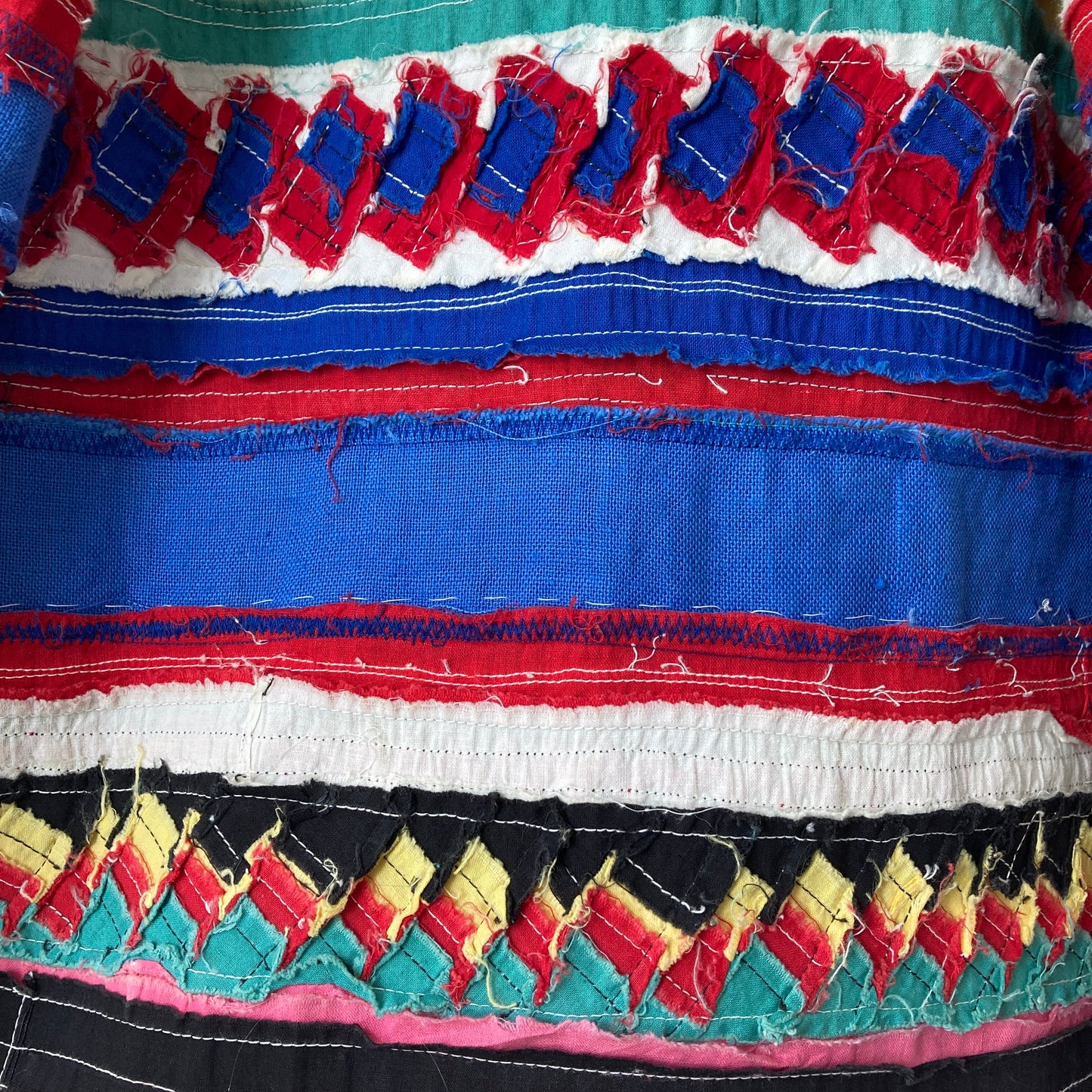 A short-sleeved shirt made from brightly coloured seminole patchwork (close-up of inside of patchwork)