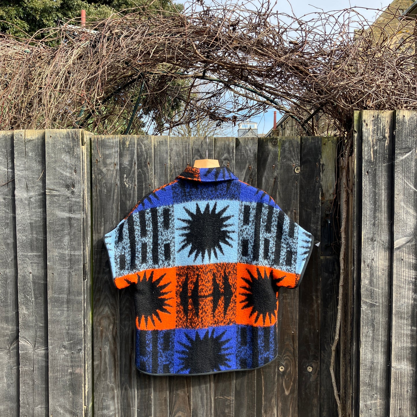 Crop-sleeved jacket made from a fabulous reclaimed blanket with starburst motifs in bright blue, light blue, black and orange (back view)
