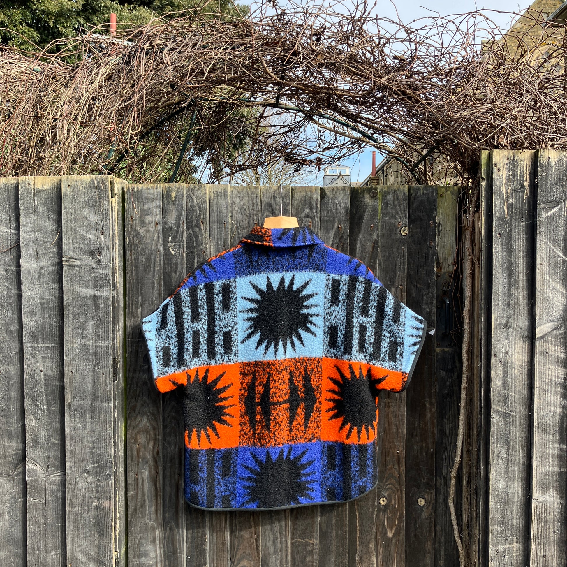 Crop-sleeved jacket made from a fabulous reclaimed blanket with starburst motifs in bright blue, light blue, black and orange (back view)
