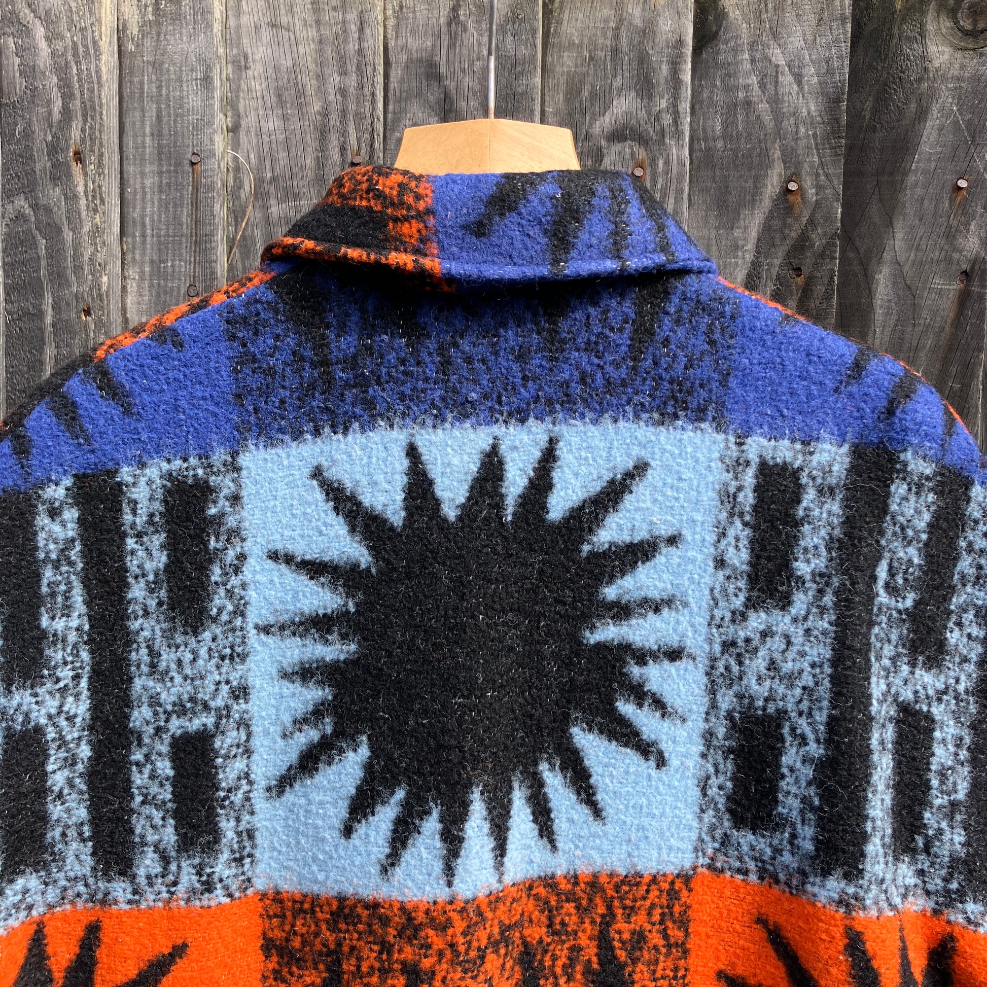 Crop-sleeved jacket made from a fabulous reclaimed blanket with starburst motifs in bright blue, light blue, black and orange (close-up of back collar)