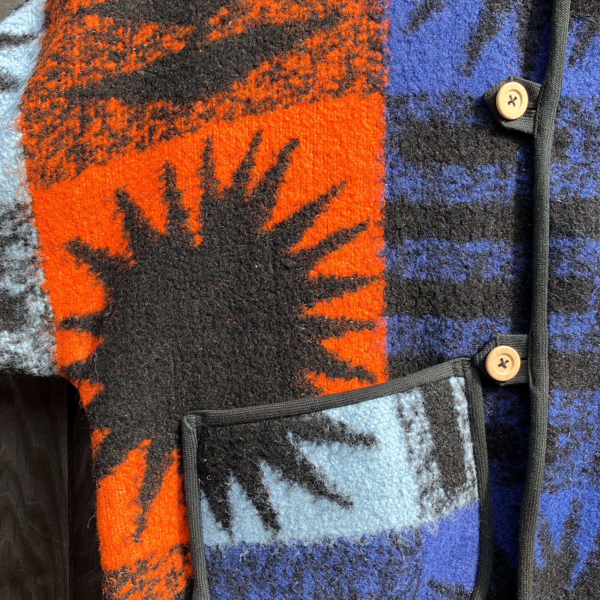 Crop-sleeved jacket made from a fabulous reclaimed blanket with starburst motifs in bright blue, light blue, black and orange. Close up of one of the patch pockets