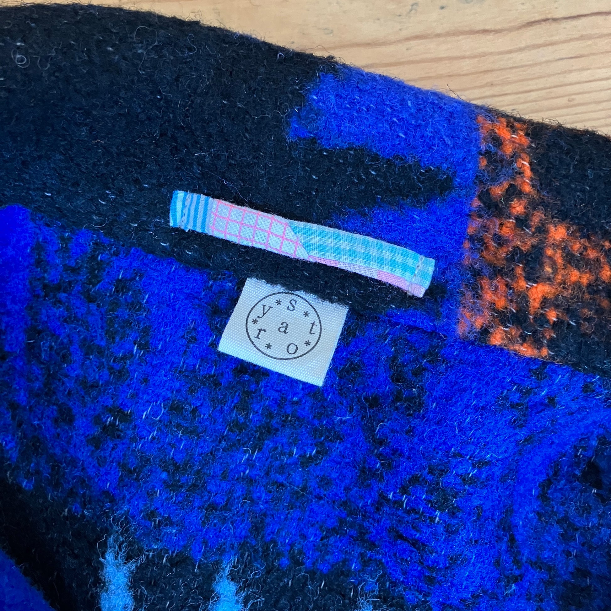 Crop-sleeved jacket made from a fabulous reclaimed blanket with starburst motifs in bright blue, light blue, black and orange (close-up of the hanging loop made from a scrap of patchwork)