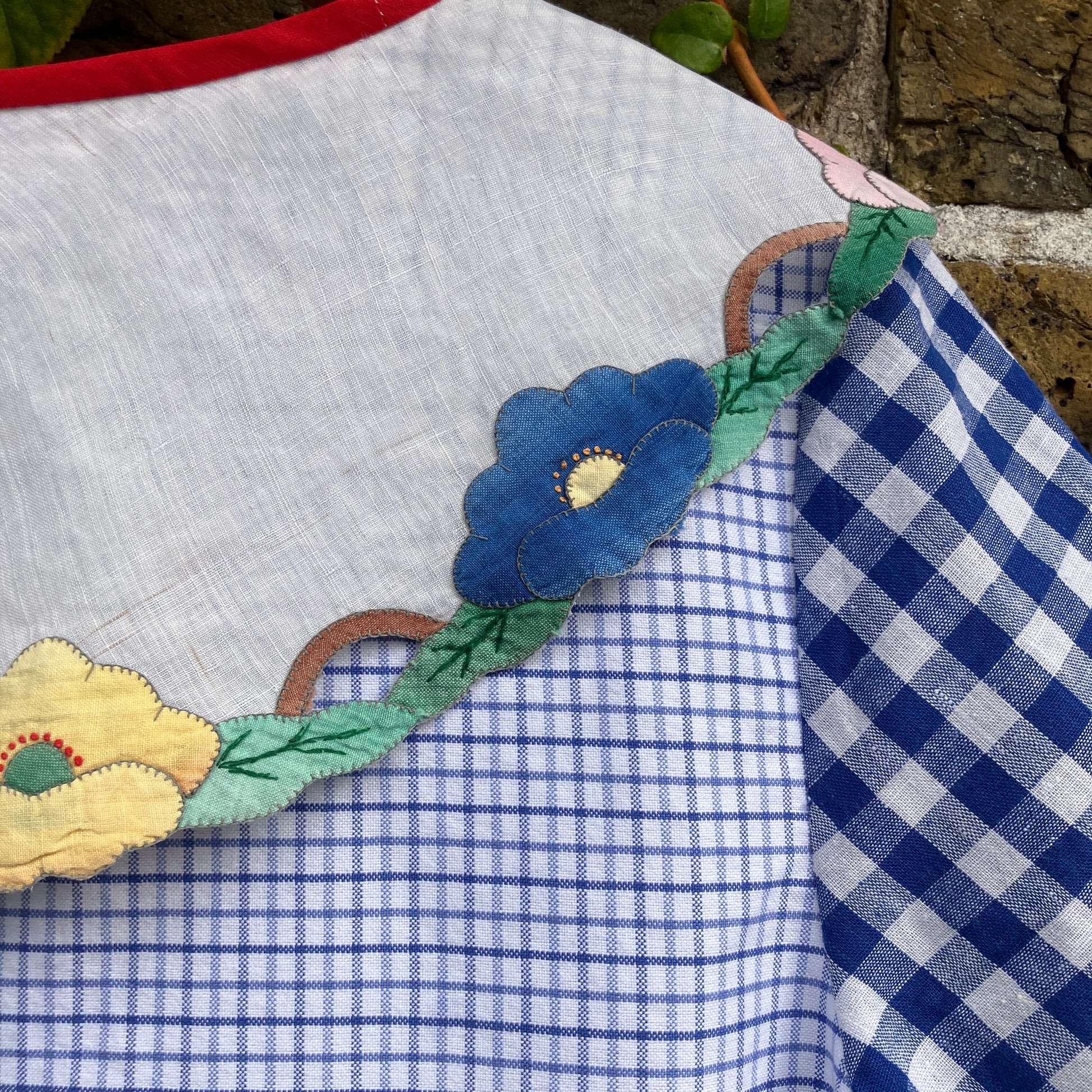 Short-sleeved top made from found offcuts of checked linen and a round floral table mat forming the collar.