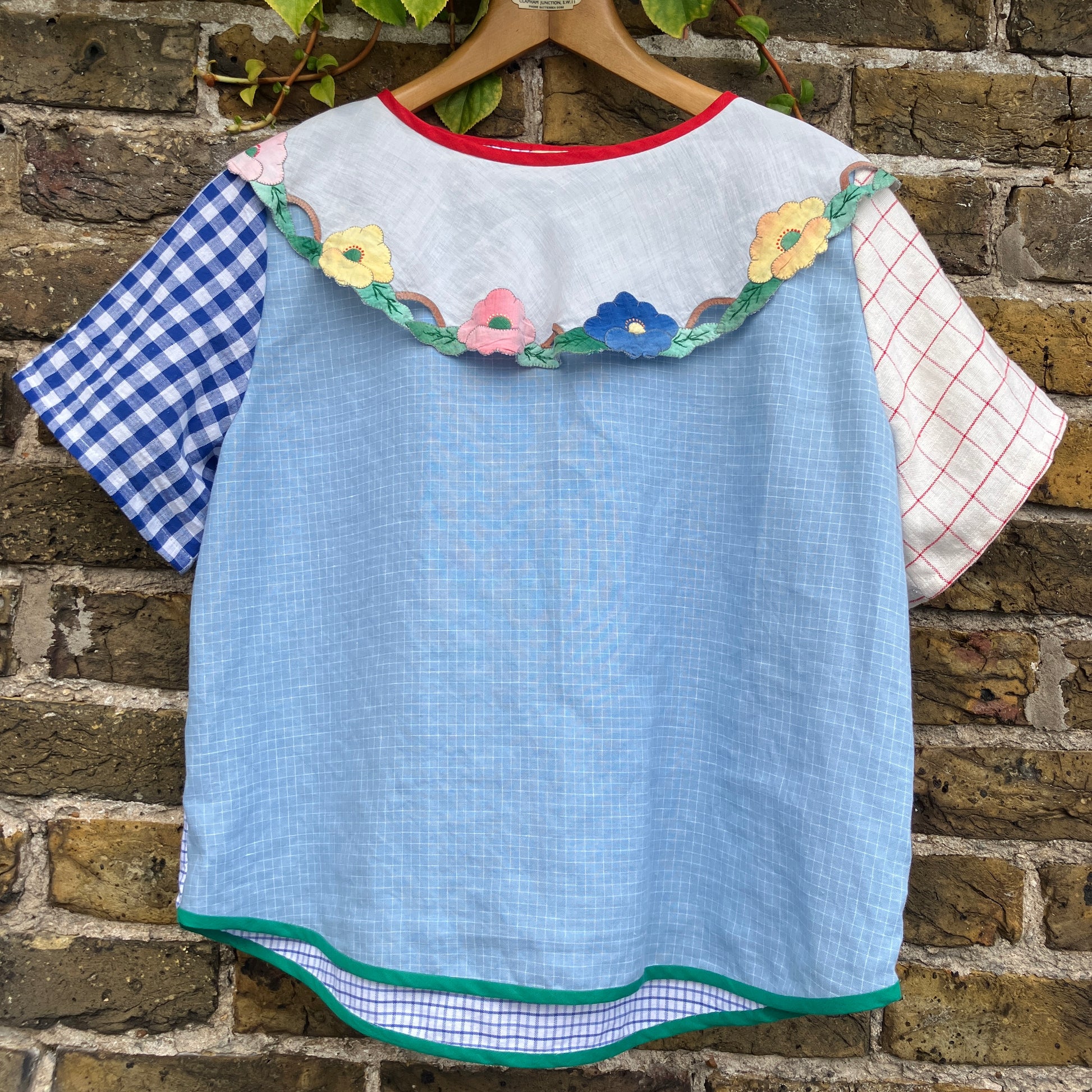 Short-sleeved top made from found offcuts of checked linen and a round floral table mat forming the collar.