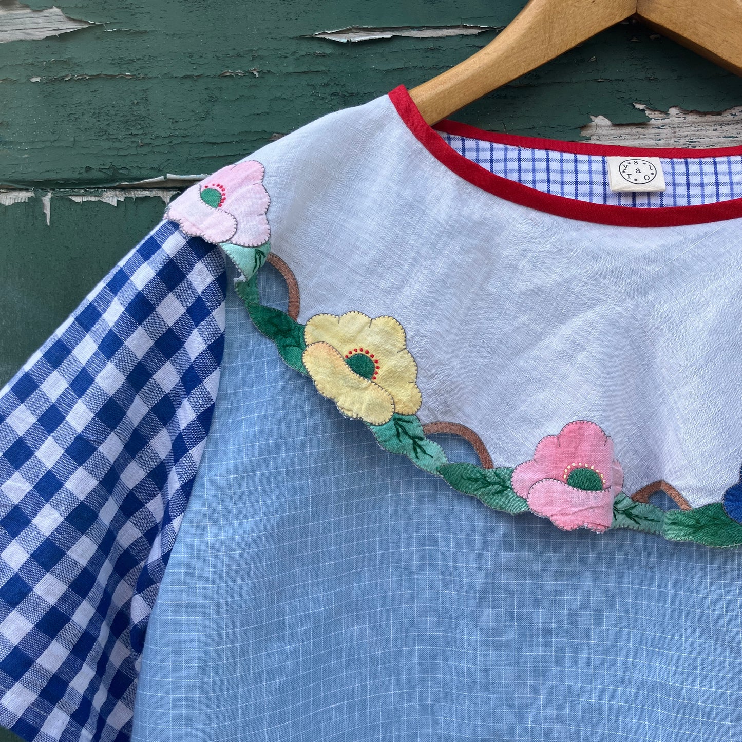 Short-sleeved top made from found offcuts of checked linen and a round floral table mat forming the collar.